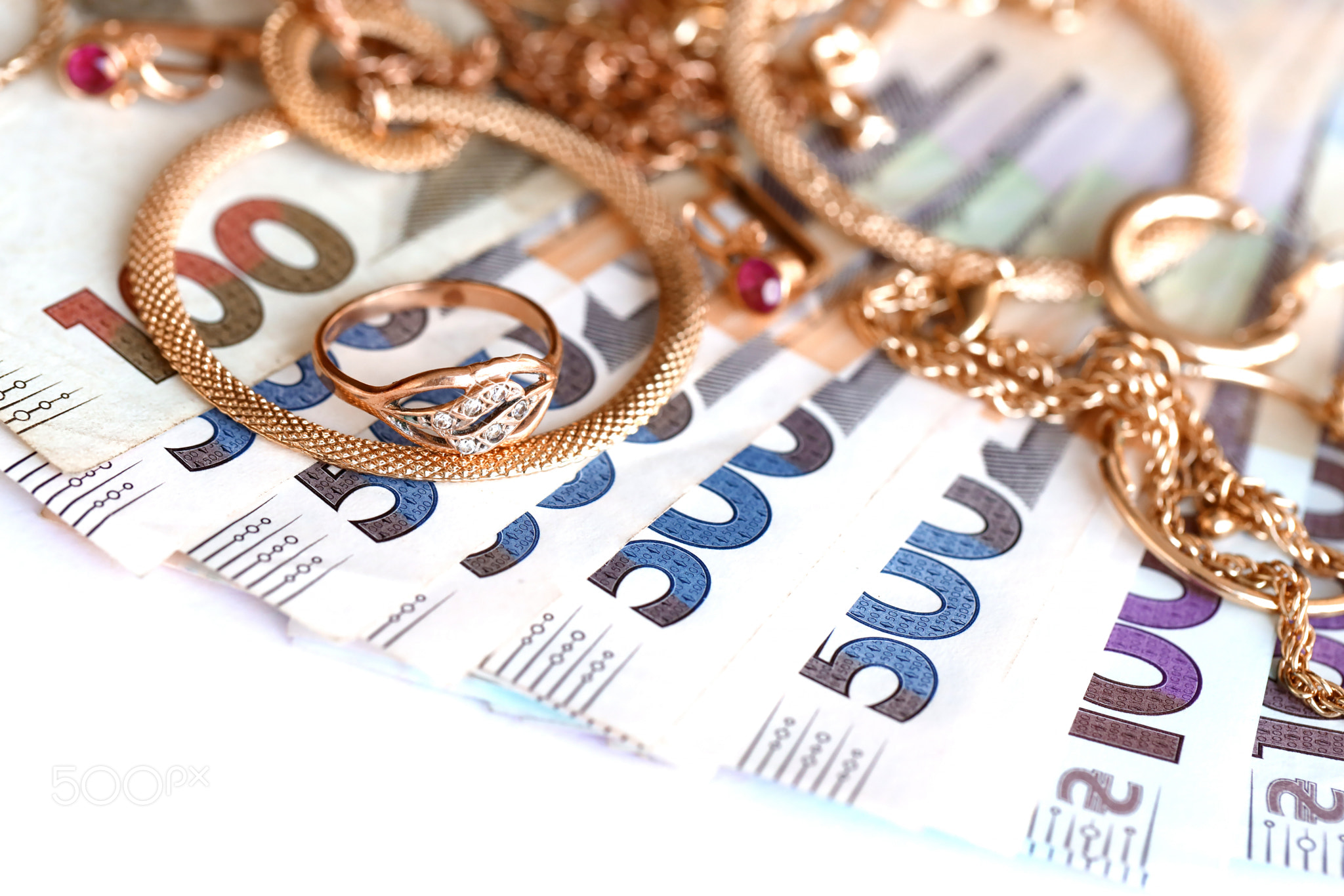 Many expensive golden jewerly rings, earrings and necklaces with big amount of Ukrainian money bills