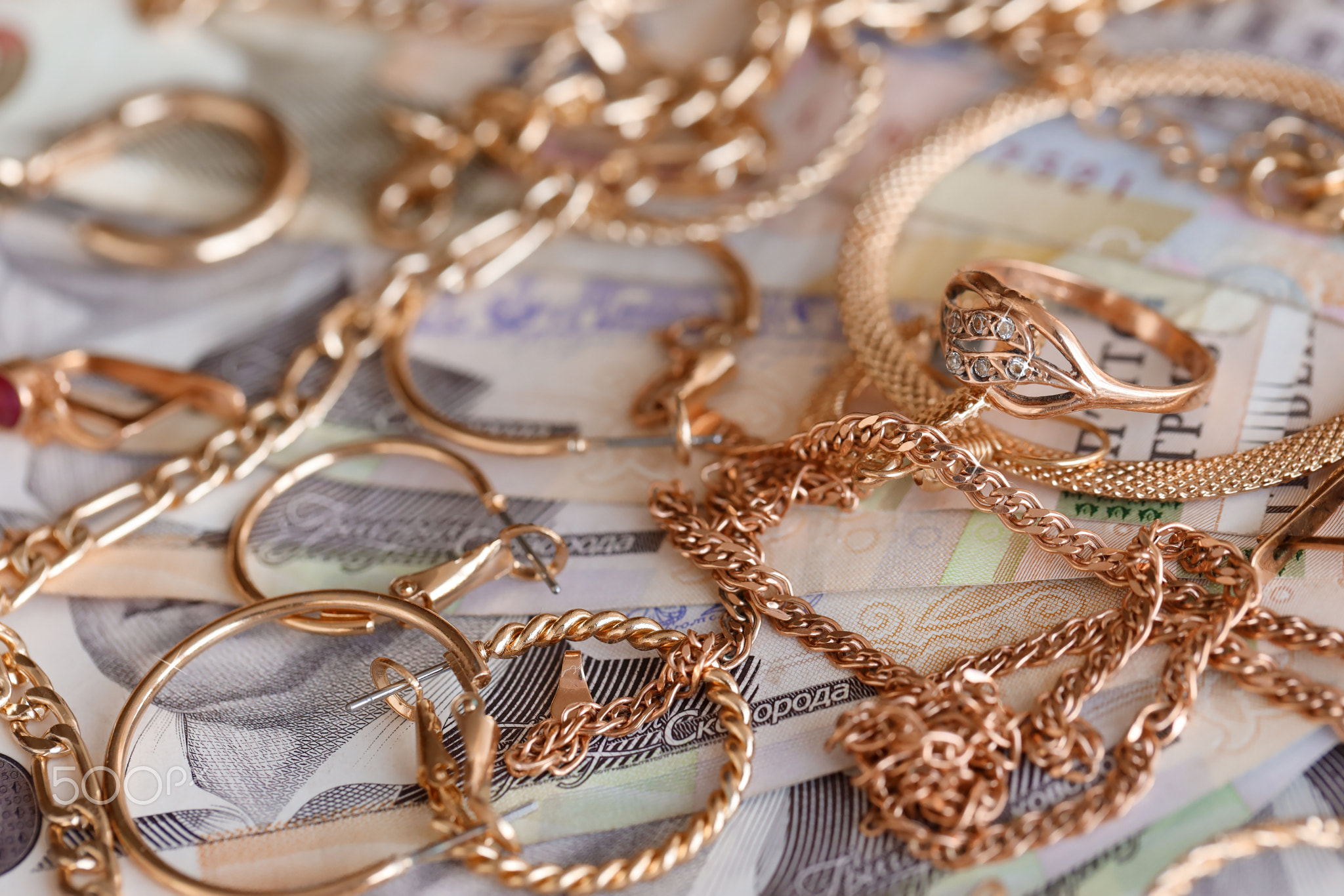 Many expensive golden jewerly rings, earrings and necklaces with big amount of Ukrainian money bills