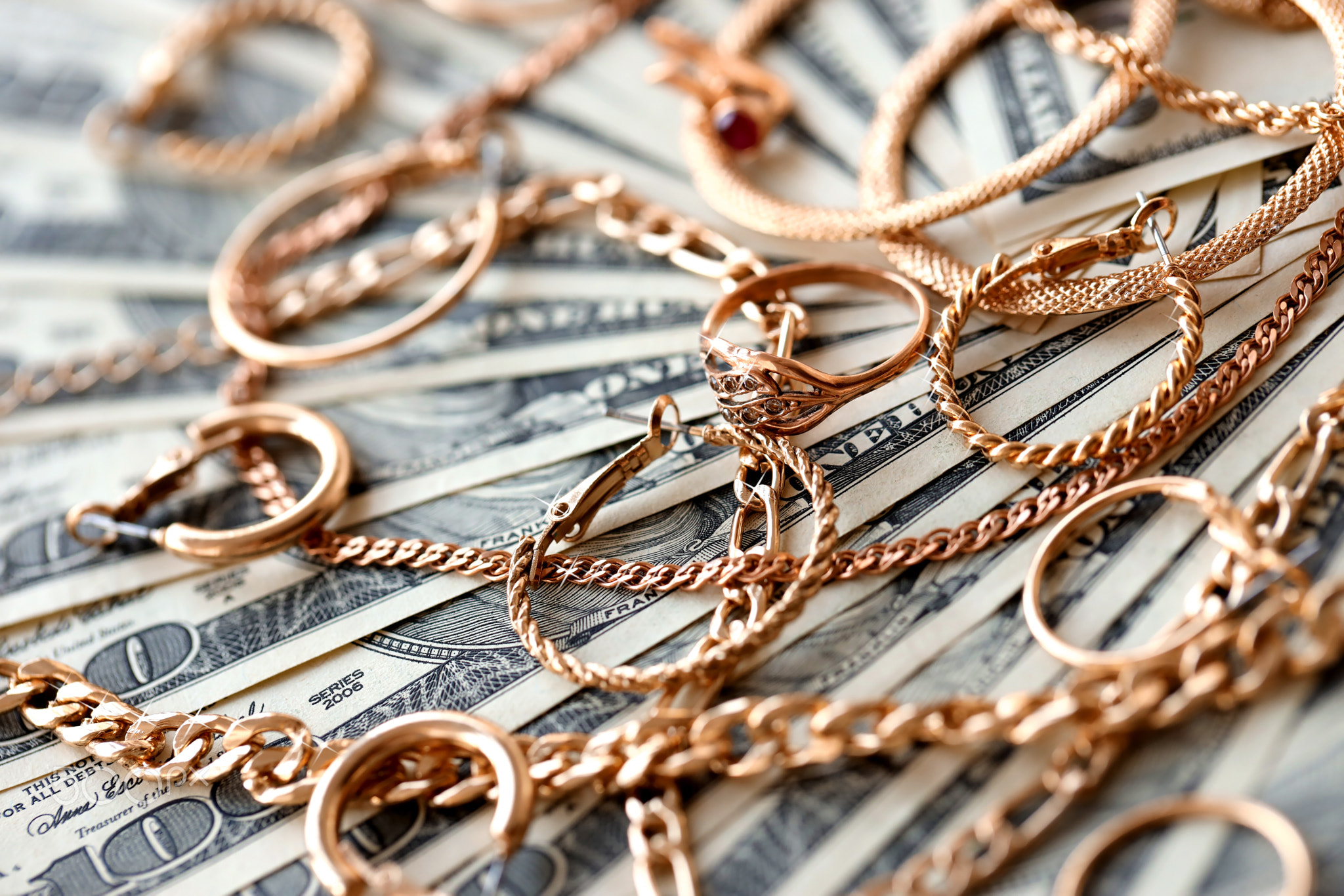 Many expensive golden jewerly rings, earrings and necklaces on big amount of US dollar bills close