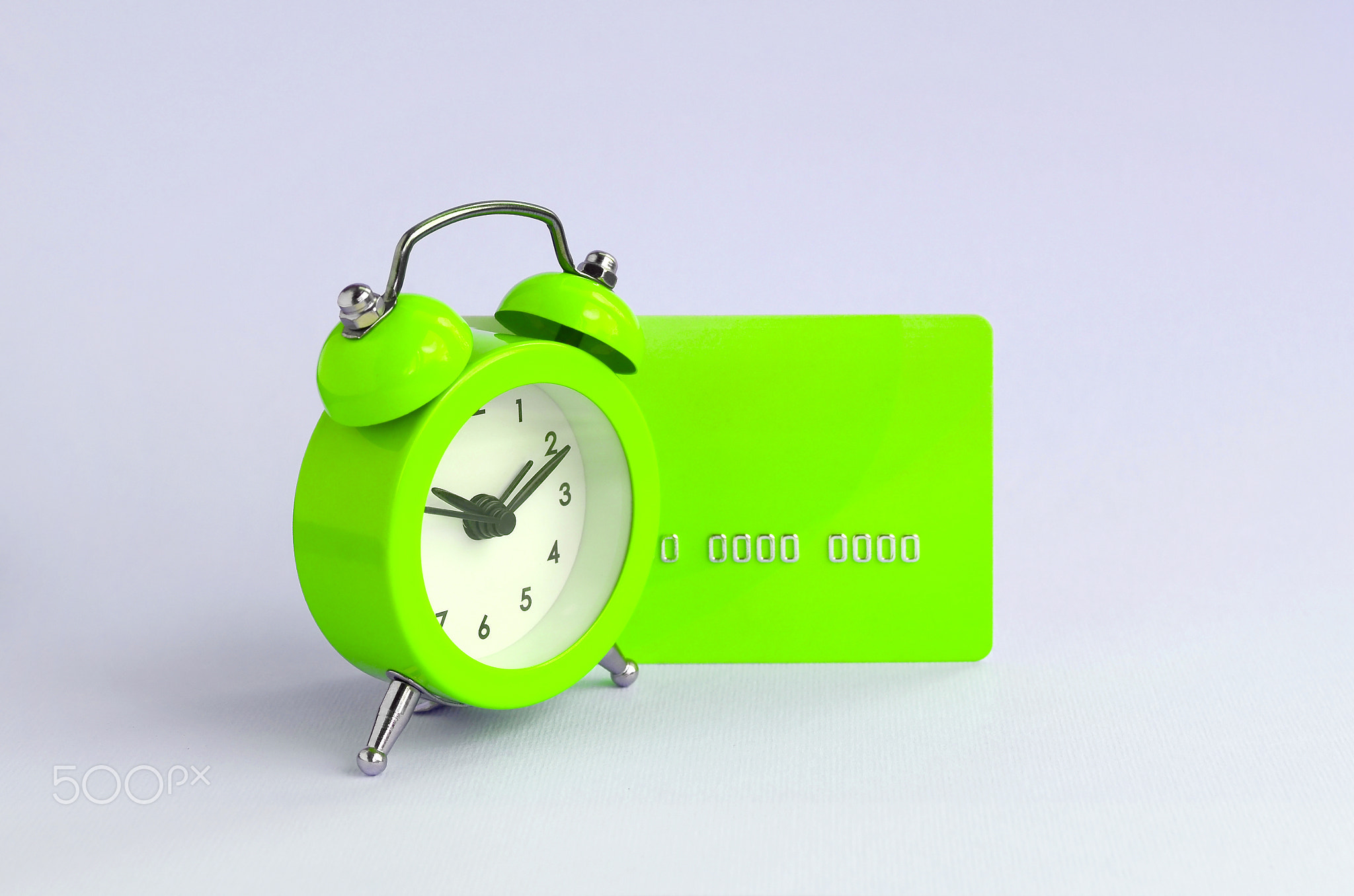 Small green alarm clock and blue credit card