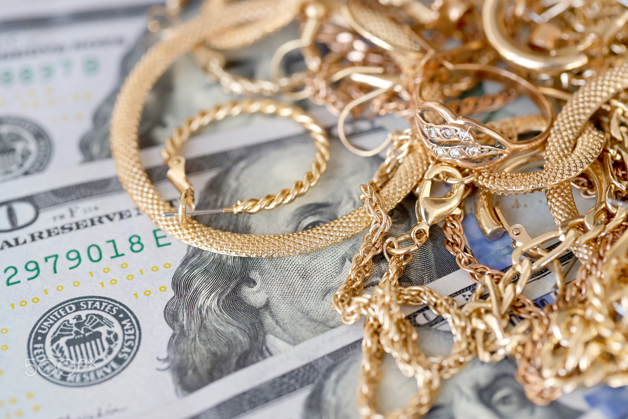 Many expensive golden jewerly rings, earrings and necklaces with big amount of US dollar bills on