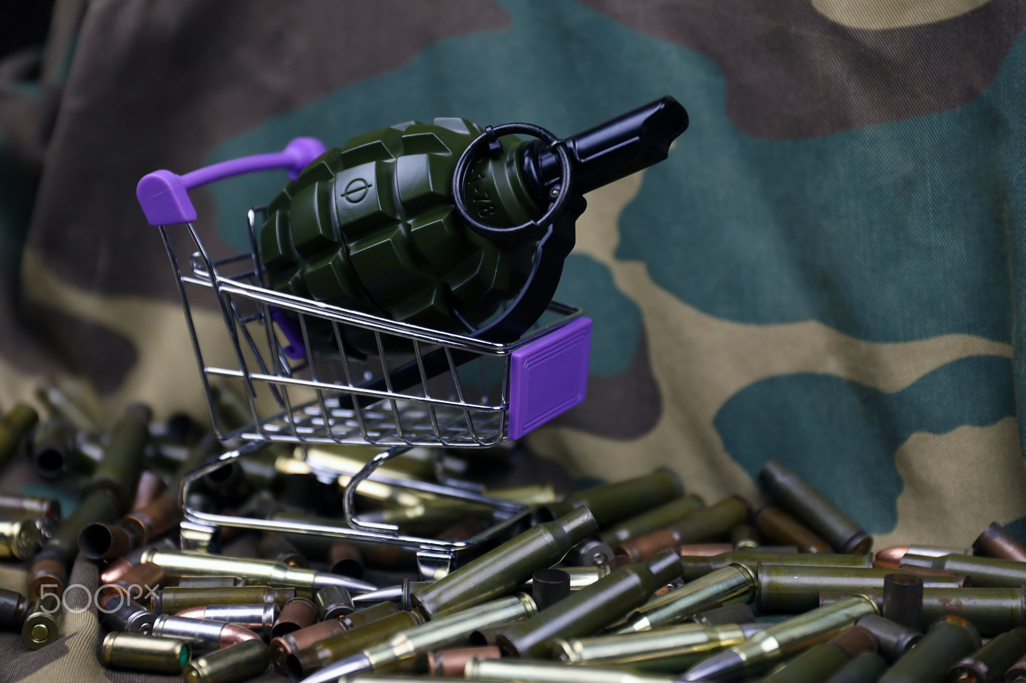 Rifle cartridges in small shopping cart. Big caliber ammo cartridges and hand grenades with a small