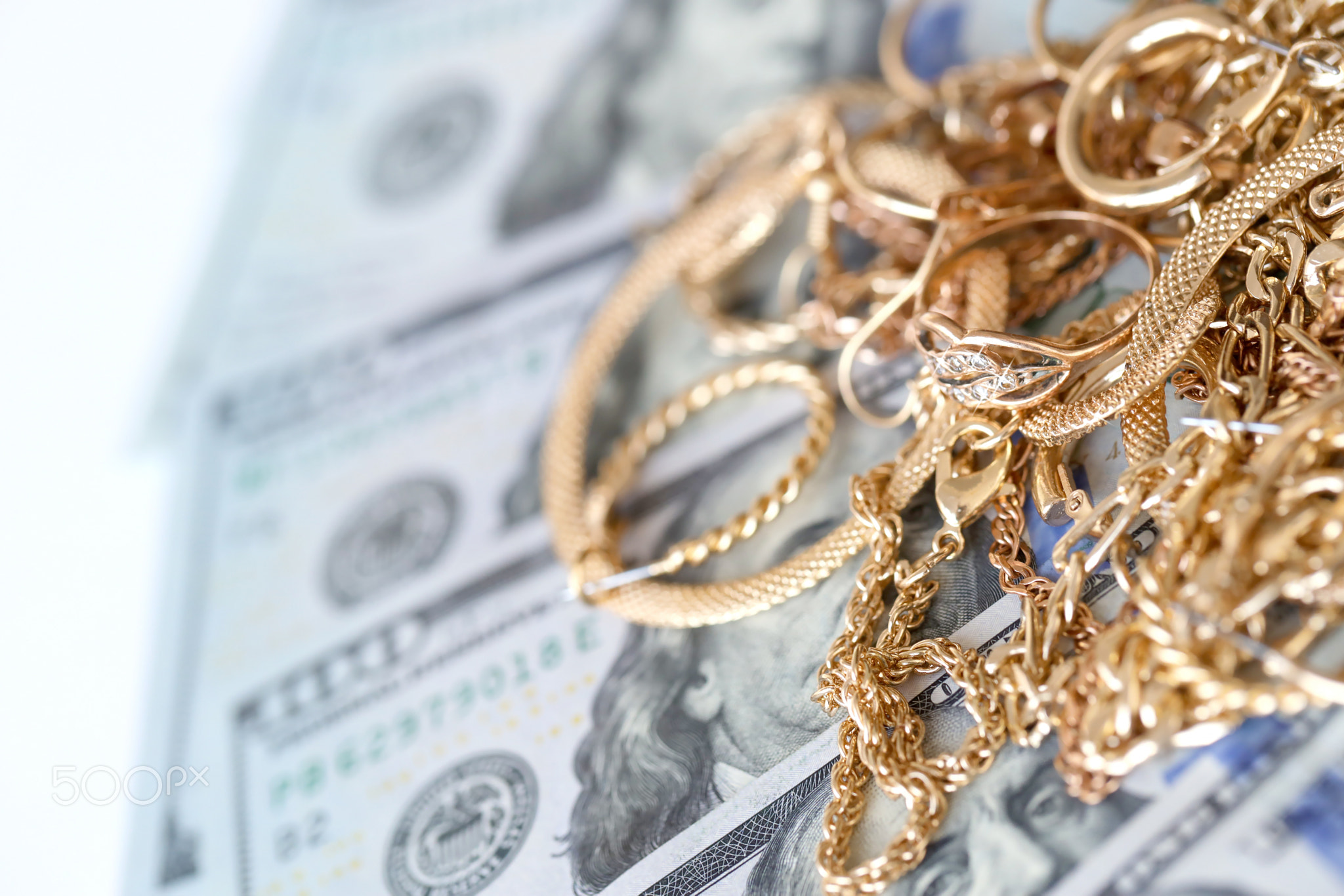 Many expensive golden jewerly rings, earrings and necklaces with big amount of US dollar bills on