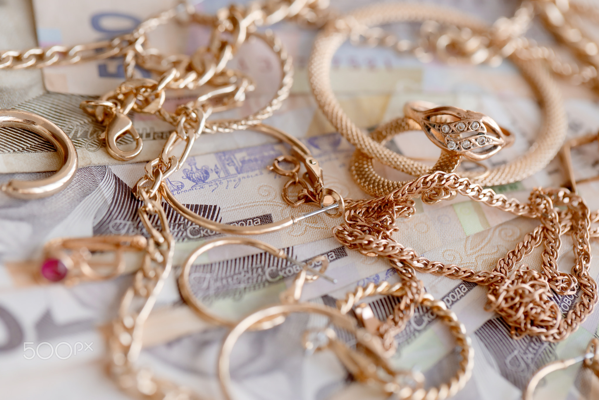 Many expensive golden jewerly rings, earrings and necklaces with big amount of Ukrainian money bills