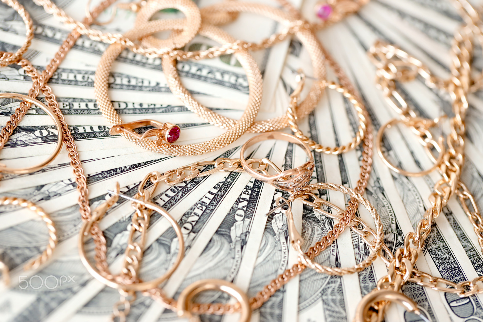 Many expensive golden jewerly rings, earrings and necklaces on big amount of US dollar bills close