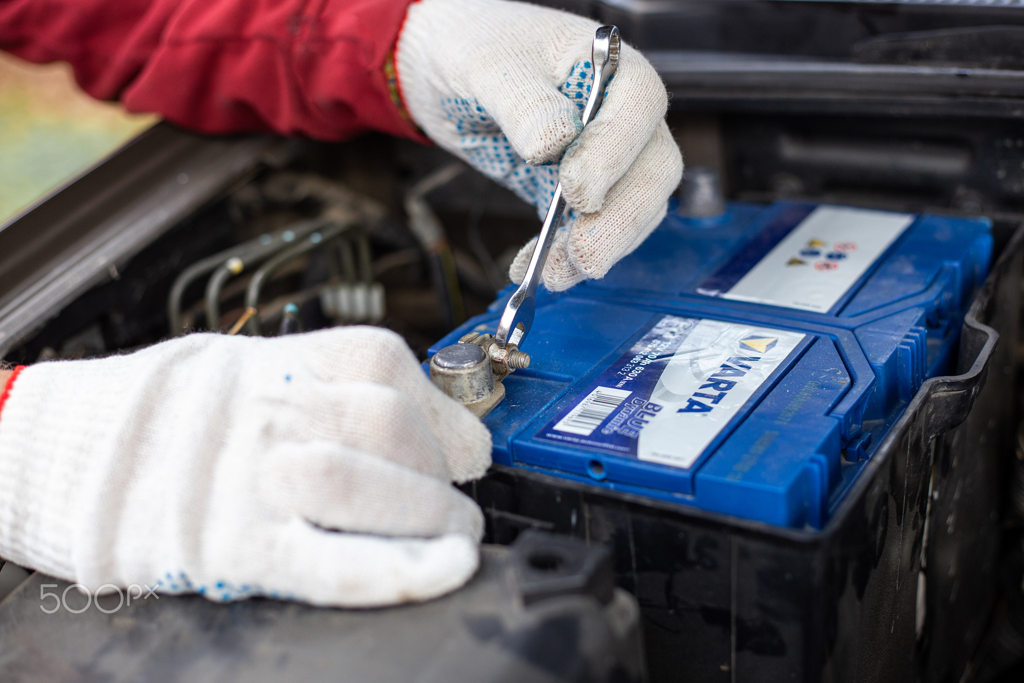 auto mechanic tightens the terminals of a car battery Varta