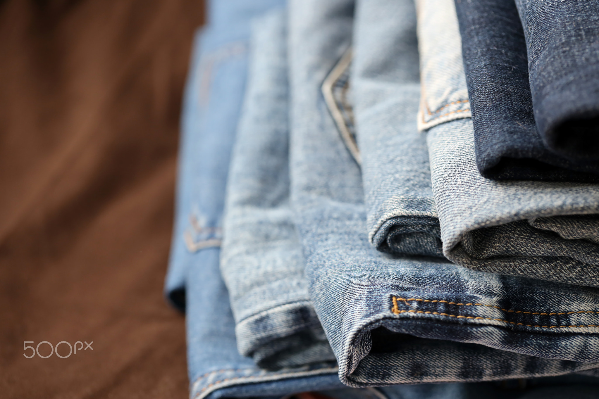 Many jeans in stack in wardrobe room. Row of pants denim jeans in closet. Concept of buy, sell