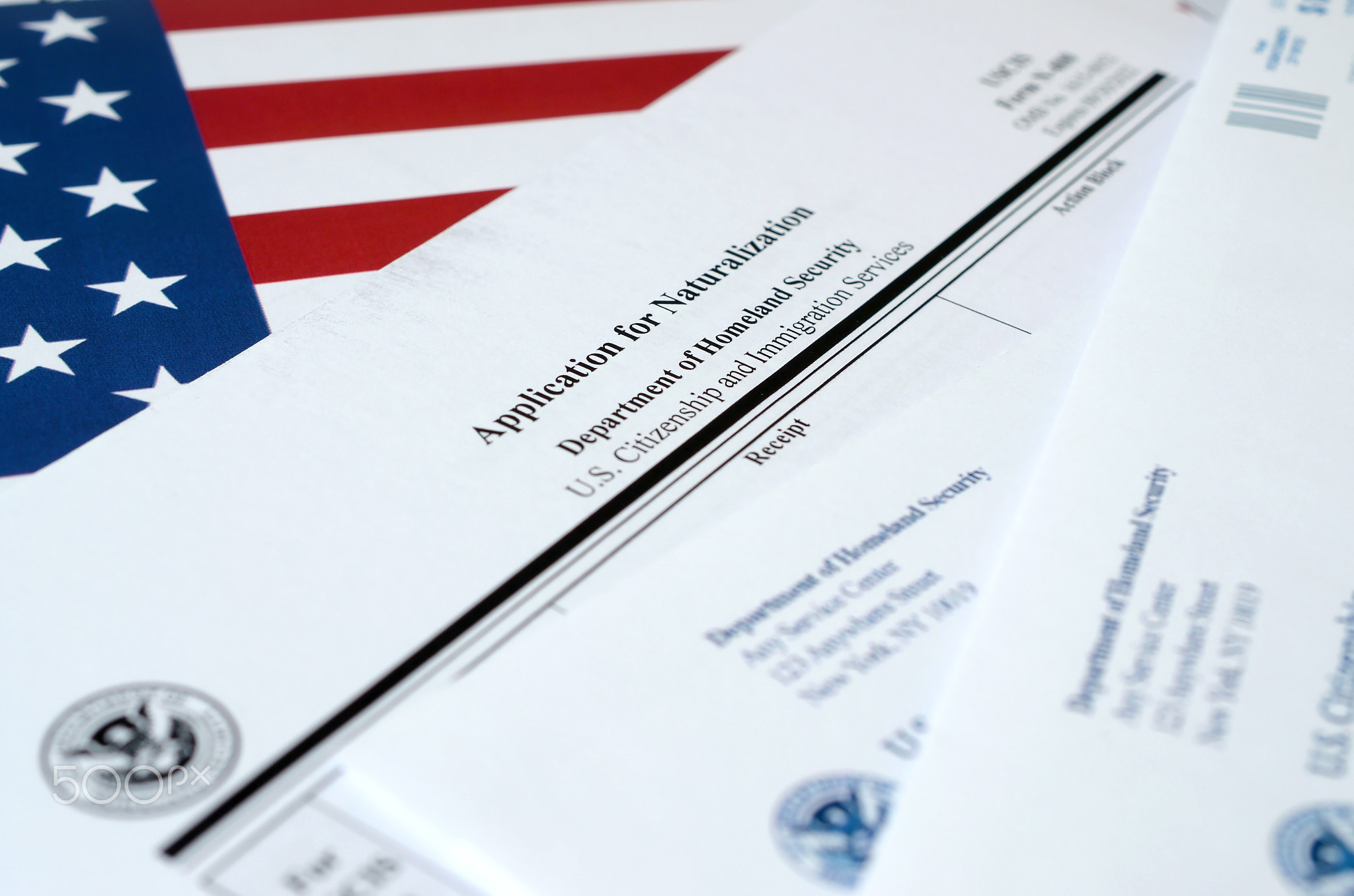 N-400 Application for Naturalization blank form lies on United States flag with envelope from