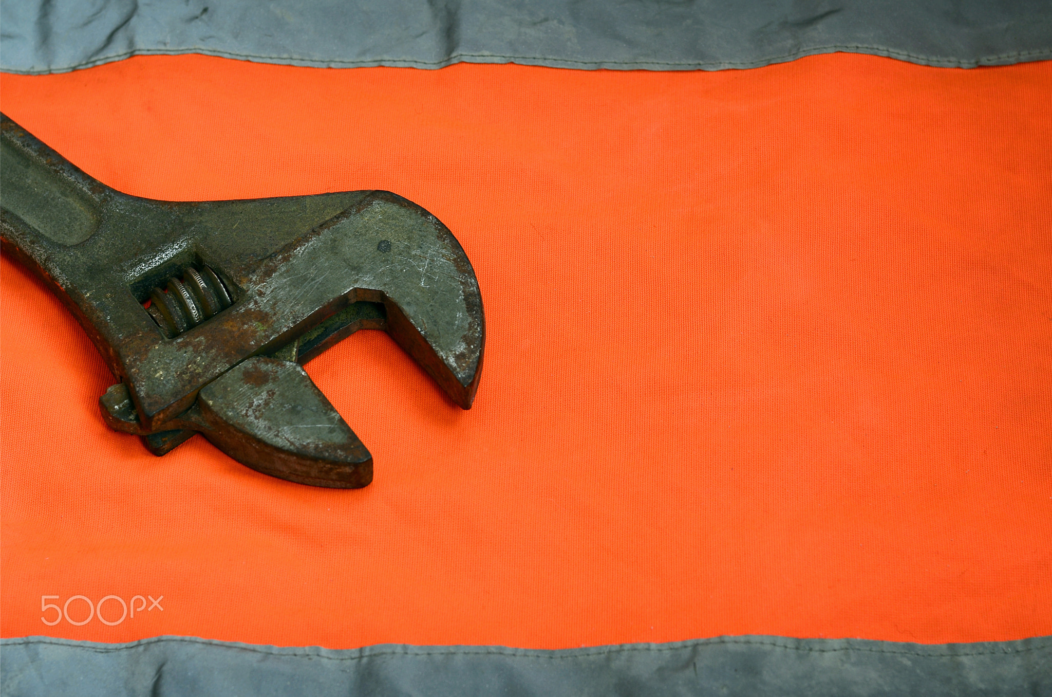 Adjustable wrench against the background of an orange signal worker shirt