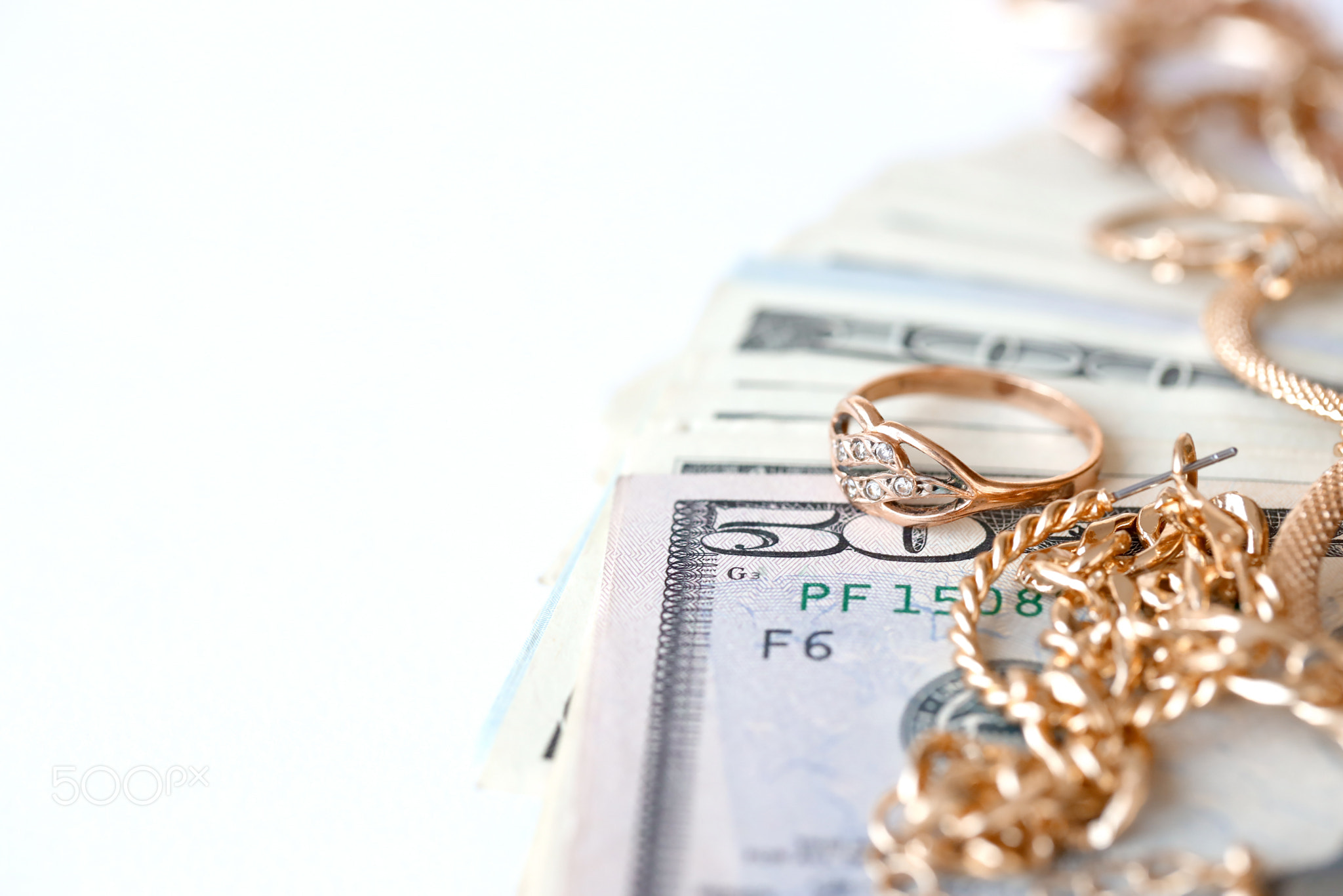 Many expensive golden jewerly rings, earrings and necklaces with big amount of US dollar bills on