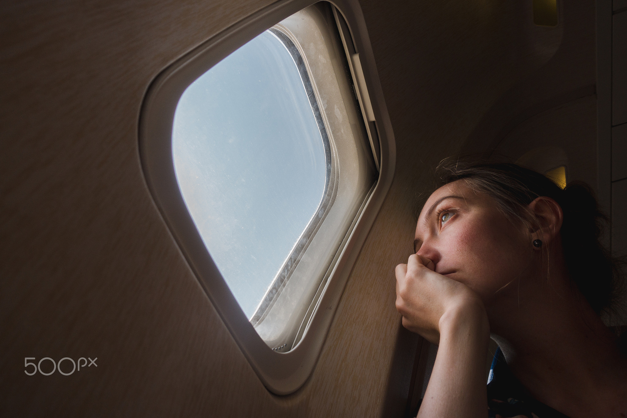 Sad woman at porthole in plane