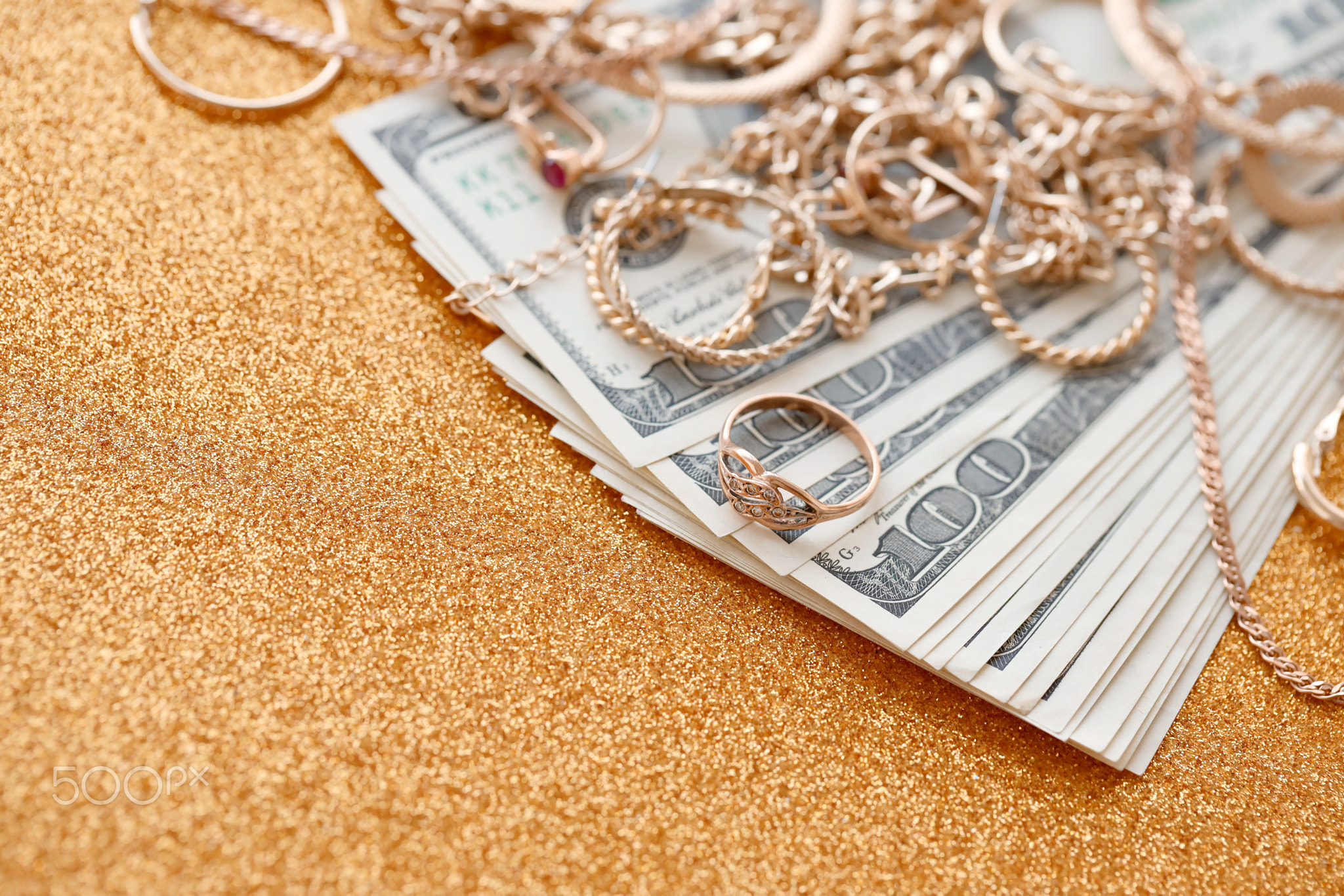 Many expensive golden jewerly rings, earrings and necklaces with big amount of US dollar bills on