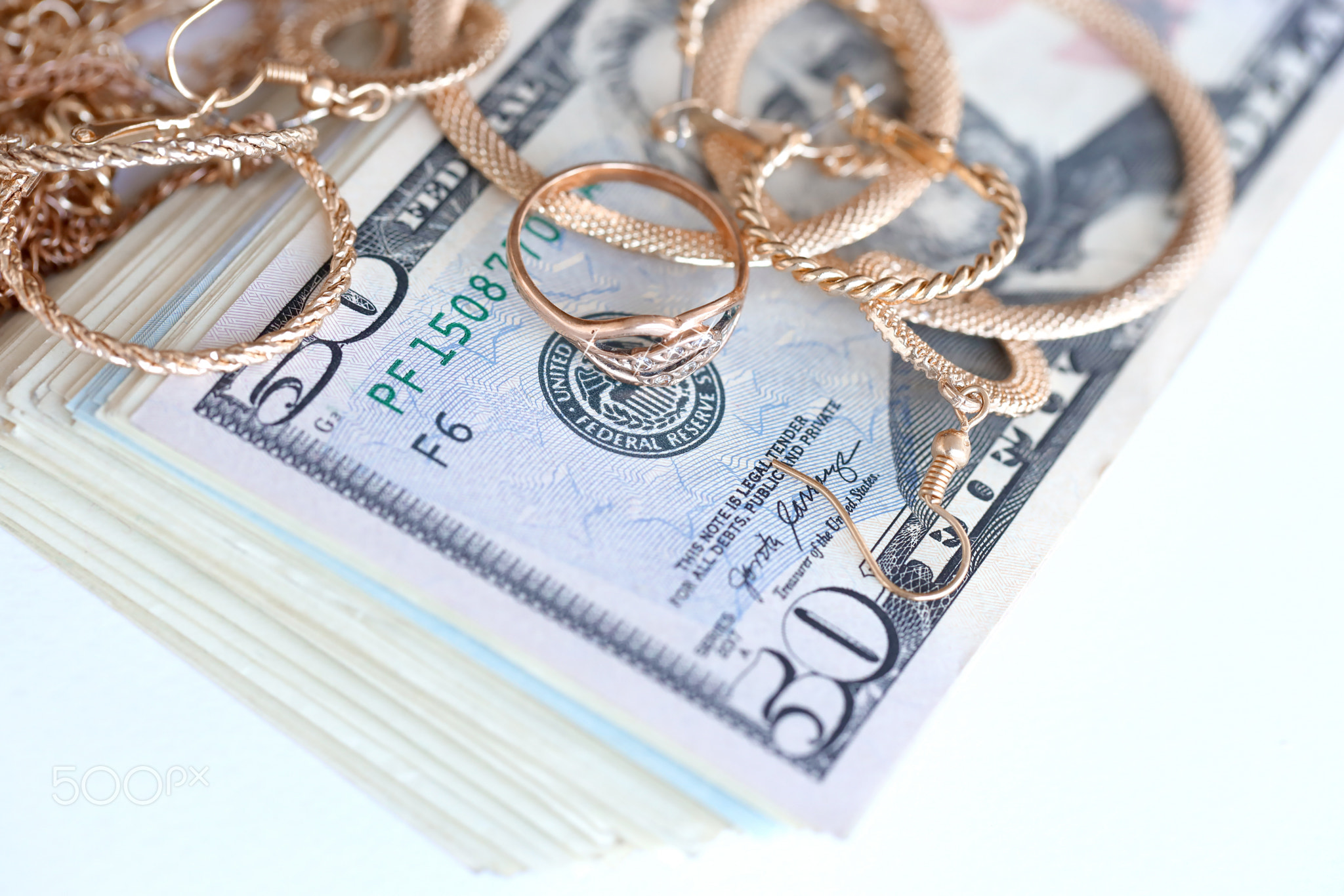 Many expensive golden jewerly rings, earrings and necklaces with big amount of US dollar bills on