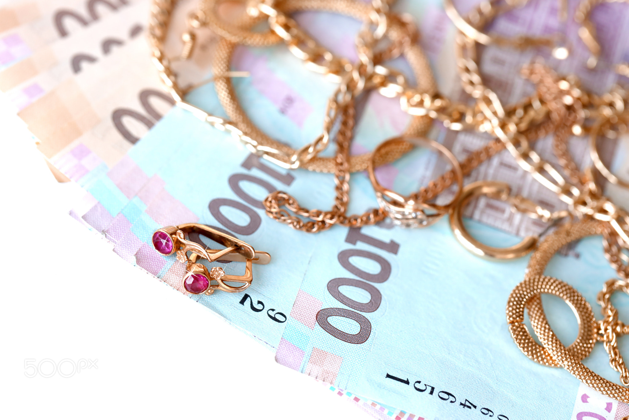 Many expensive golden jewerly rings, earrings and necklaces with big amount of Ukrainian money bills