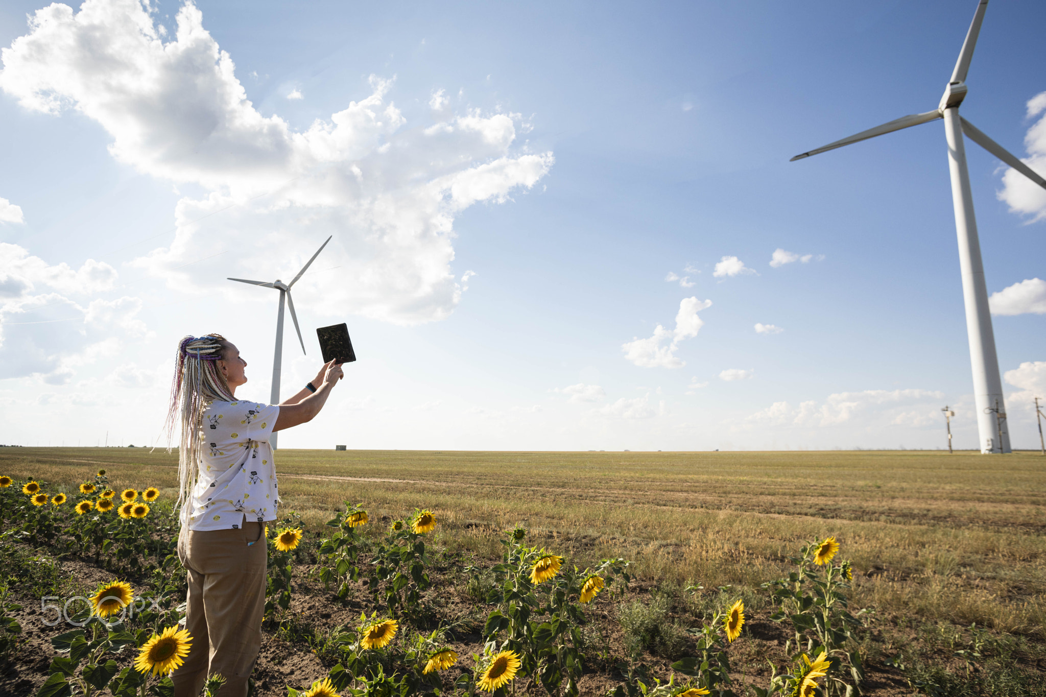 A blogger girl with bright braids shoots a story about green energy, about working with wind energy