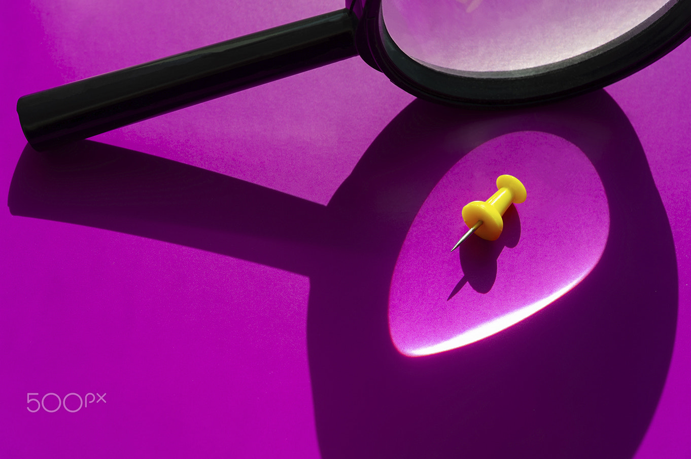 Magnifying glass and yellow push-pin on a purple background. 