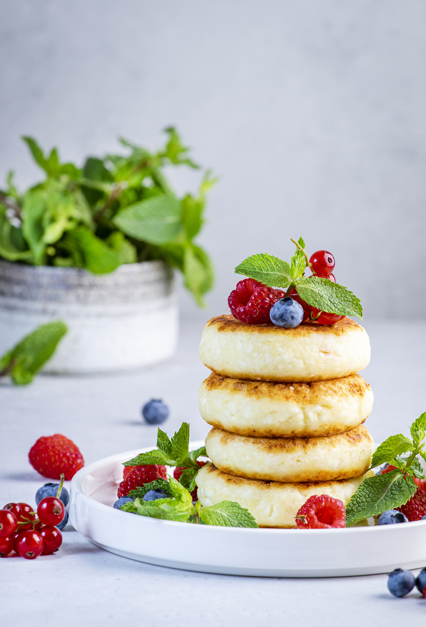 Thick pancakes with cottage cheese with blueberries, raspberries and red currants, decorated with mi