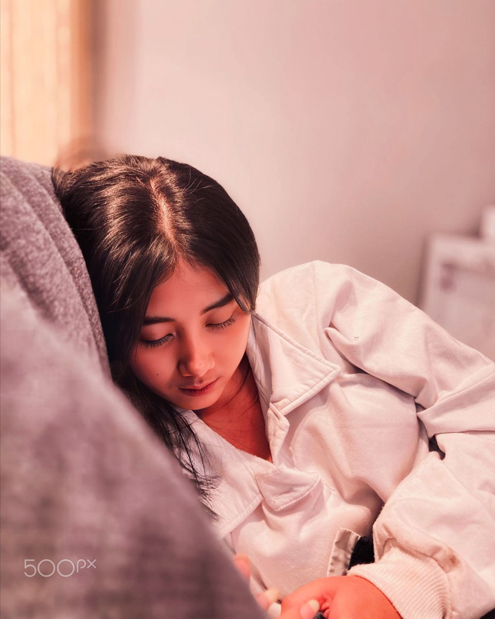 Woman using mobile phone while sitting on bed at home