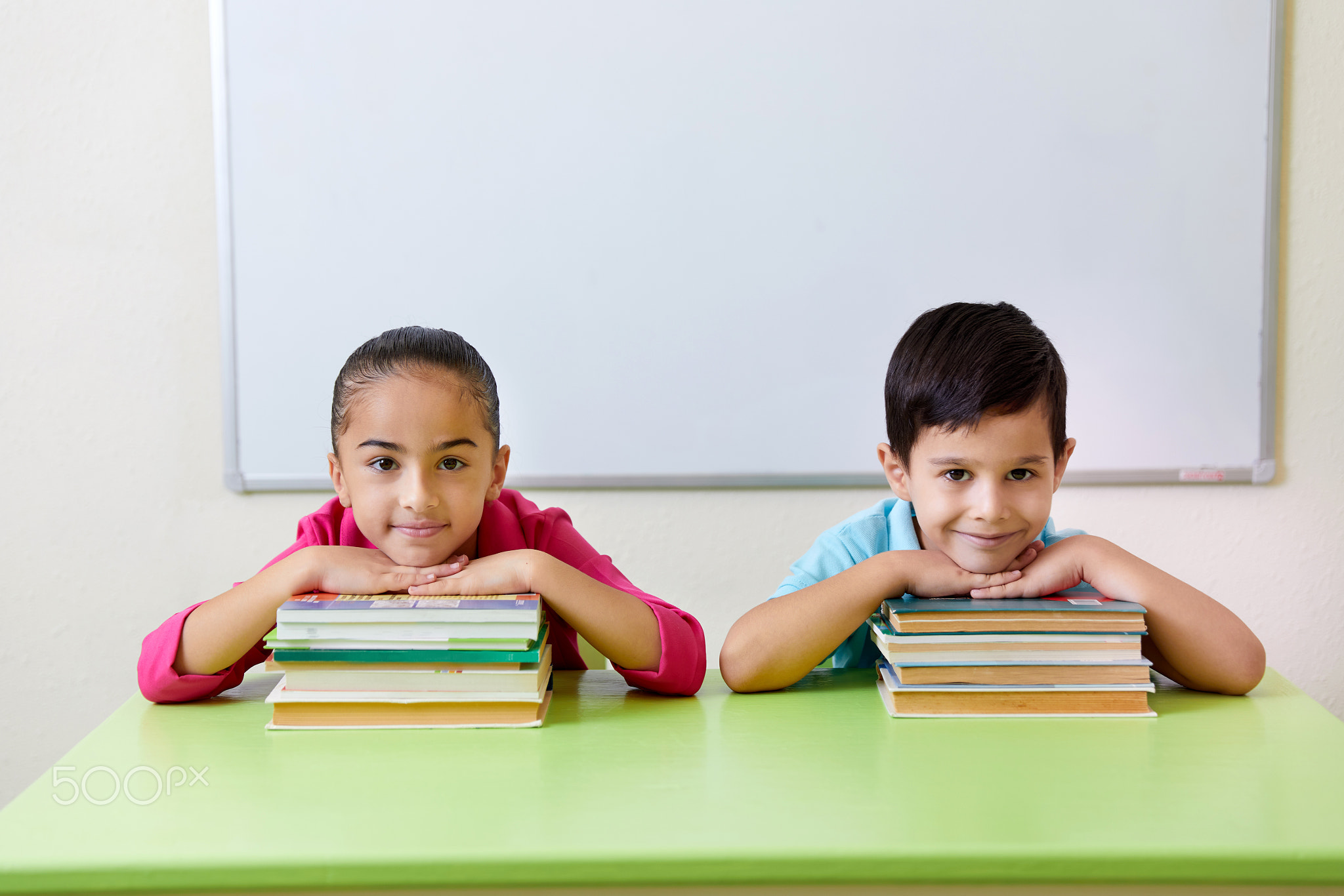Preschool children playing with books sitting at a table 