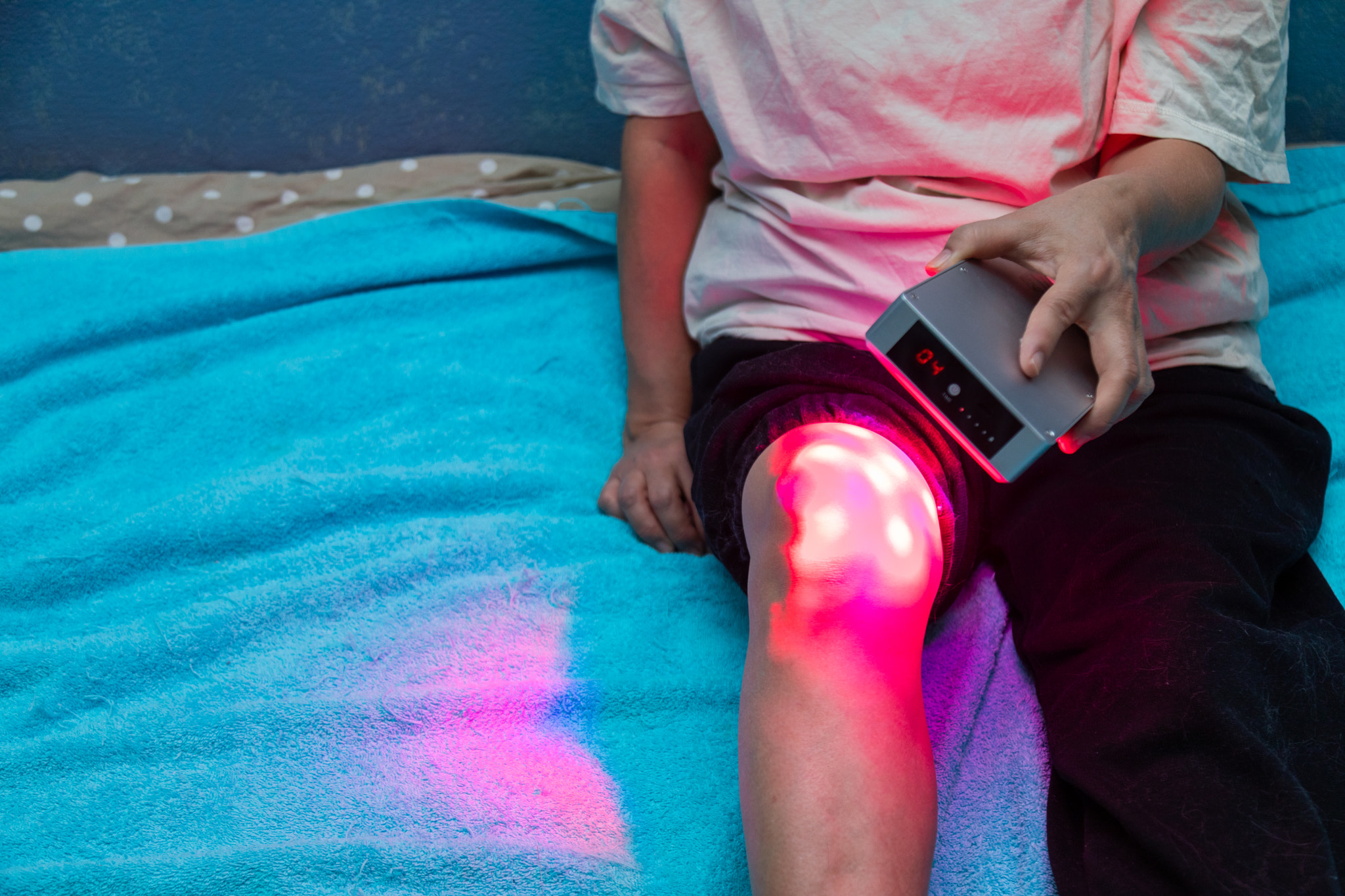 Closeup of treating sore leg with the red light therapy handheld device