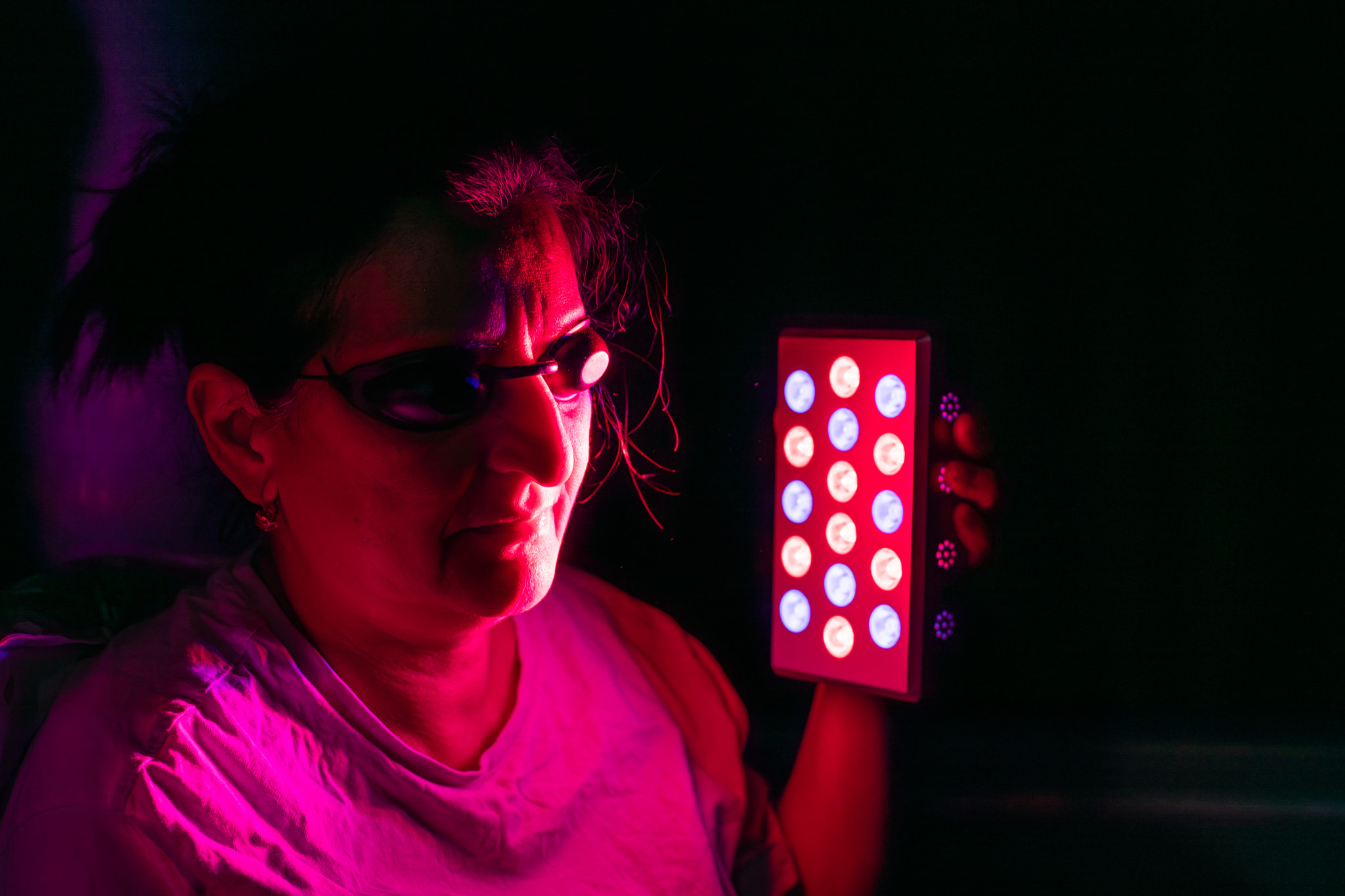 Closeup of woman doing the red light therapy session with handheld device