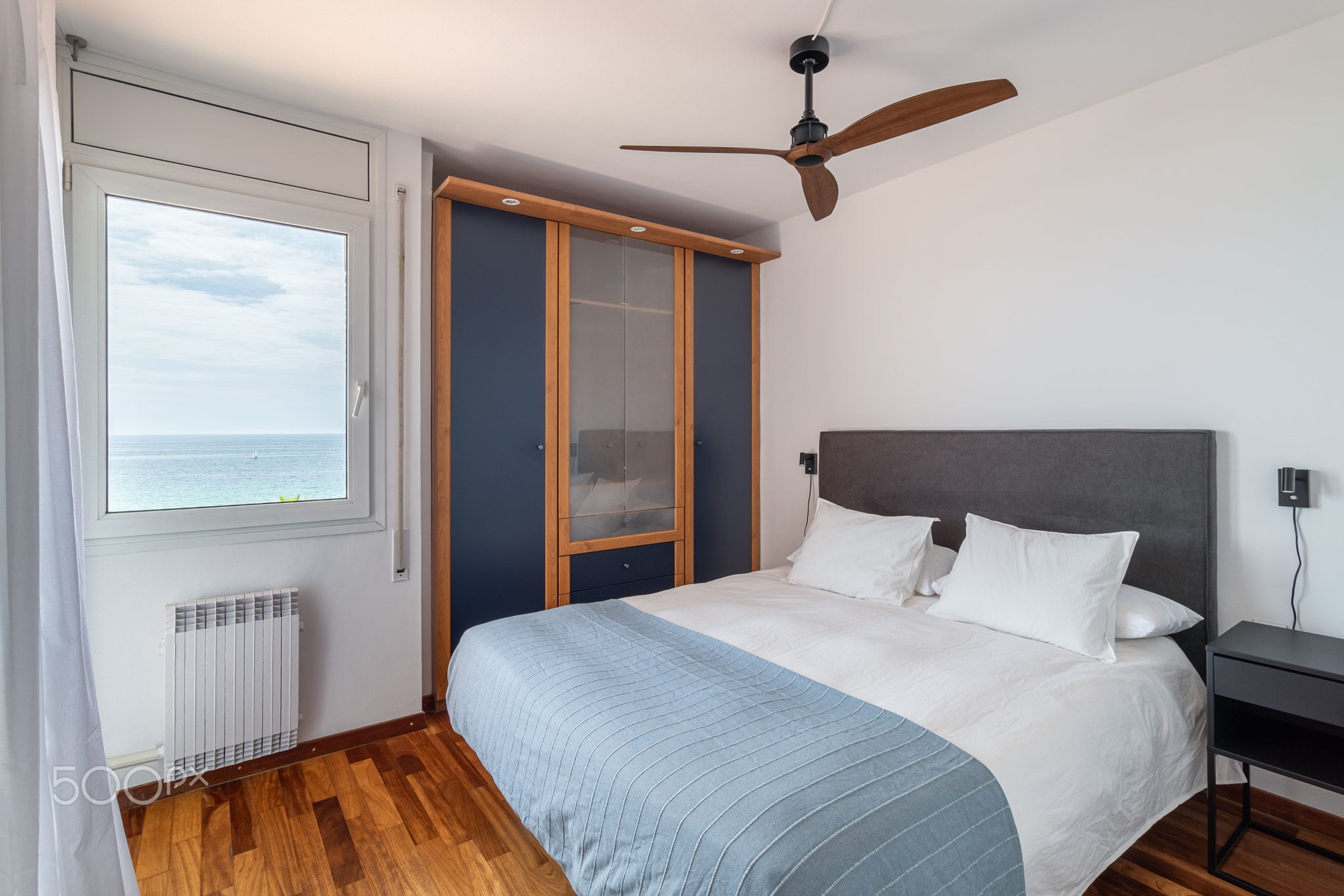 Double bed, vintage ceiling fan and wardrobe in hotel room