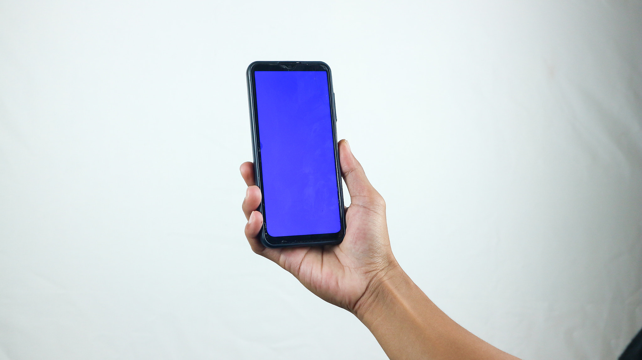 Asian man holding big smartphone with white, red, green, blue blank screen in hand, showing close to