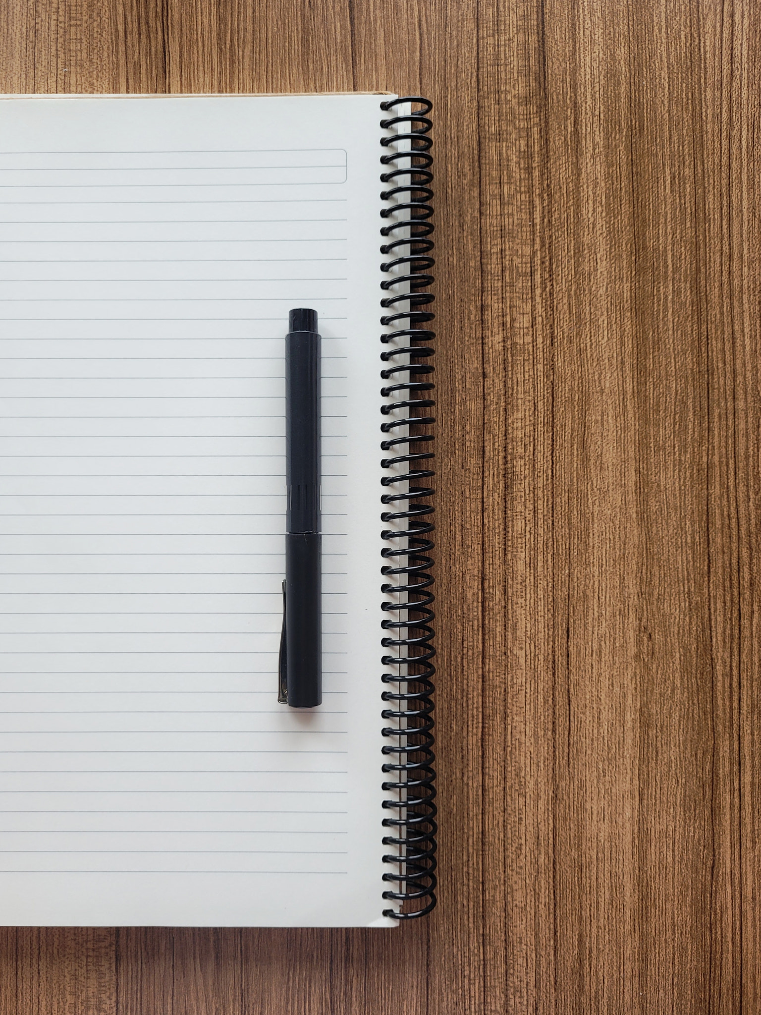 Directly above shot of spiral notebook with pen on wooden table