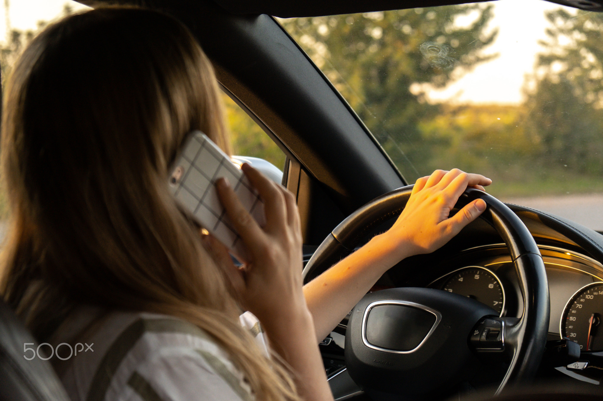 Happy young woman speaking by mobile phone while driving car. Business