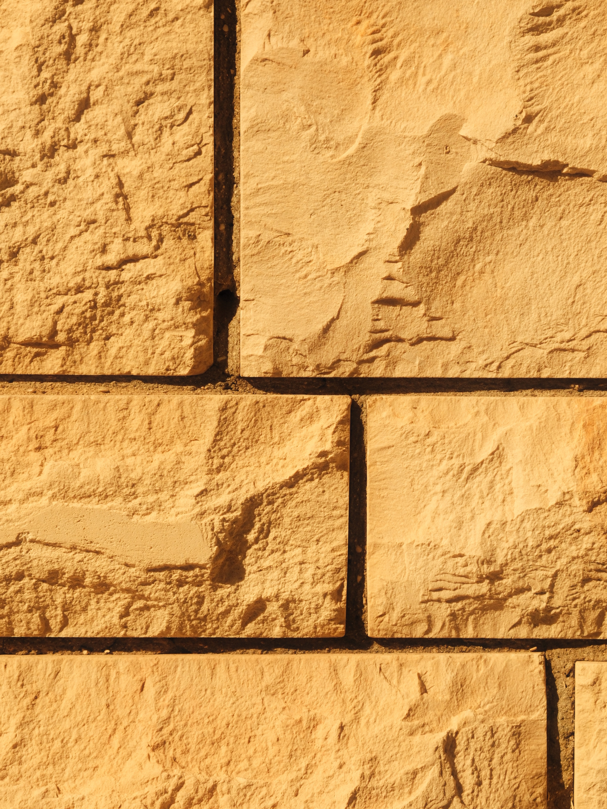 Close-up textured sandstone blocks in sunlight, seamless pattern, warm beige tones, sharp shadows