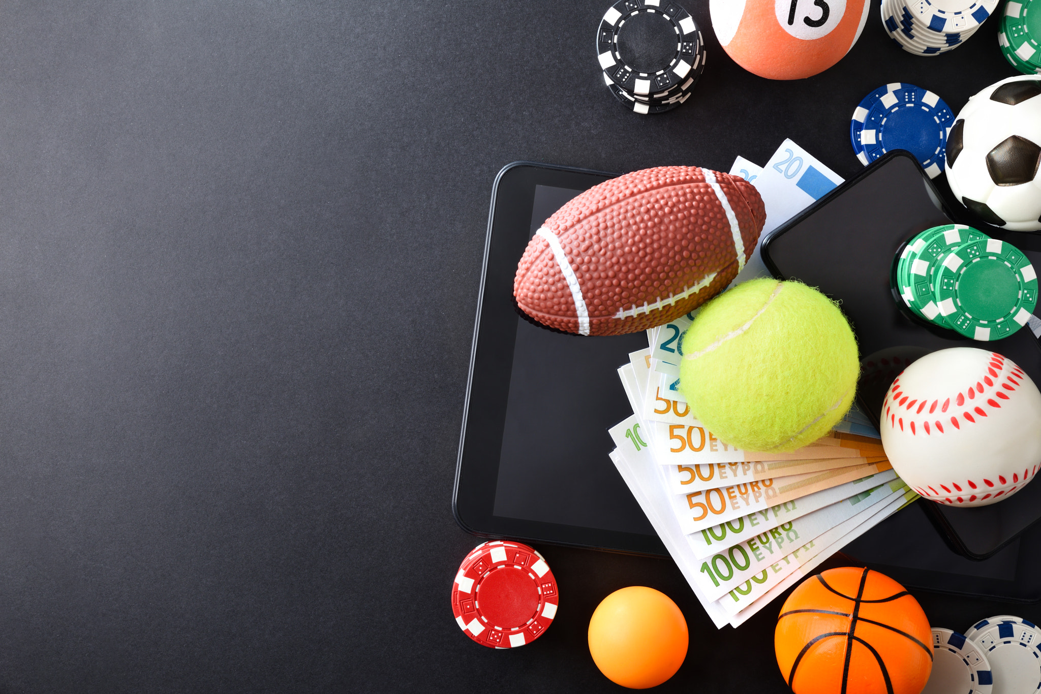 Online sports betting concept with balls and money on devices