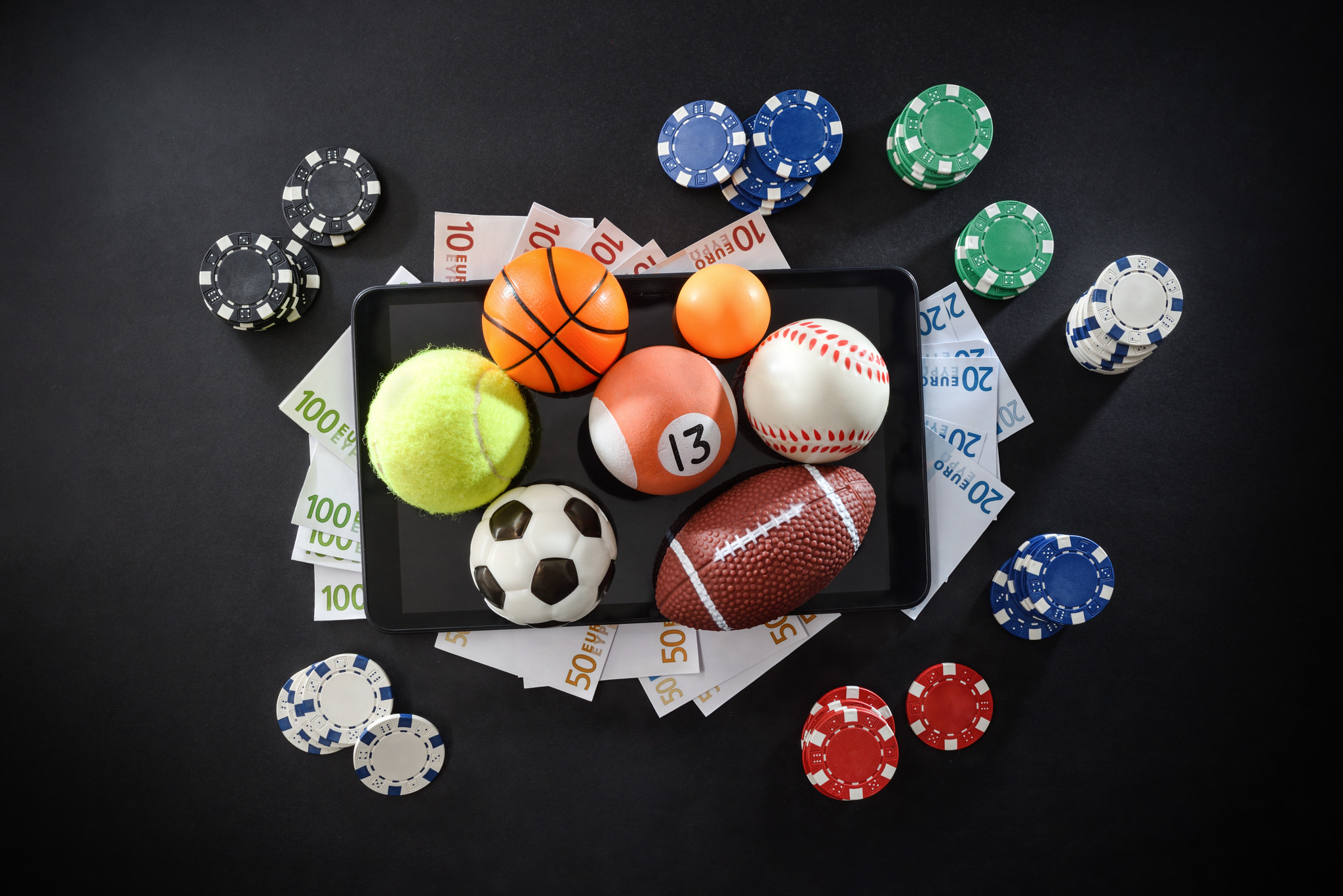 Online sports betting concept with balls and money on devices