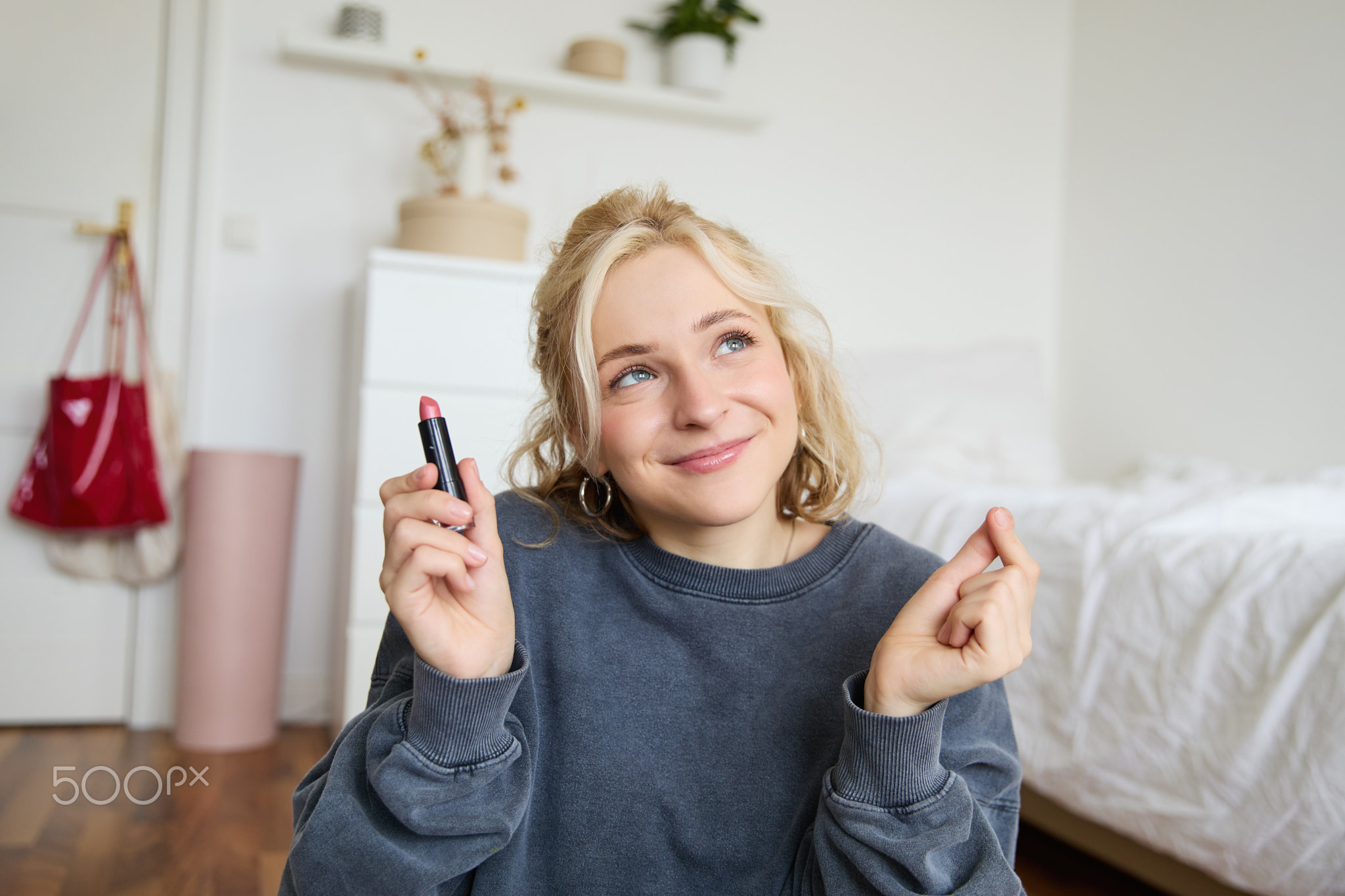 Portrait of cute, charismatic beauty blogger, woman sits in a room with lipstick in hand, talking