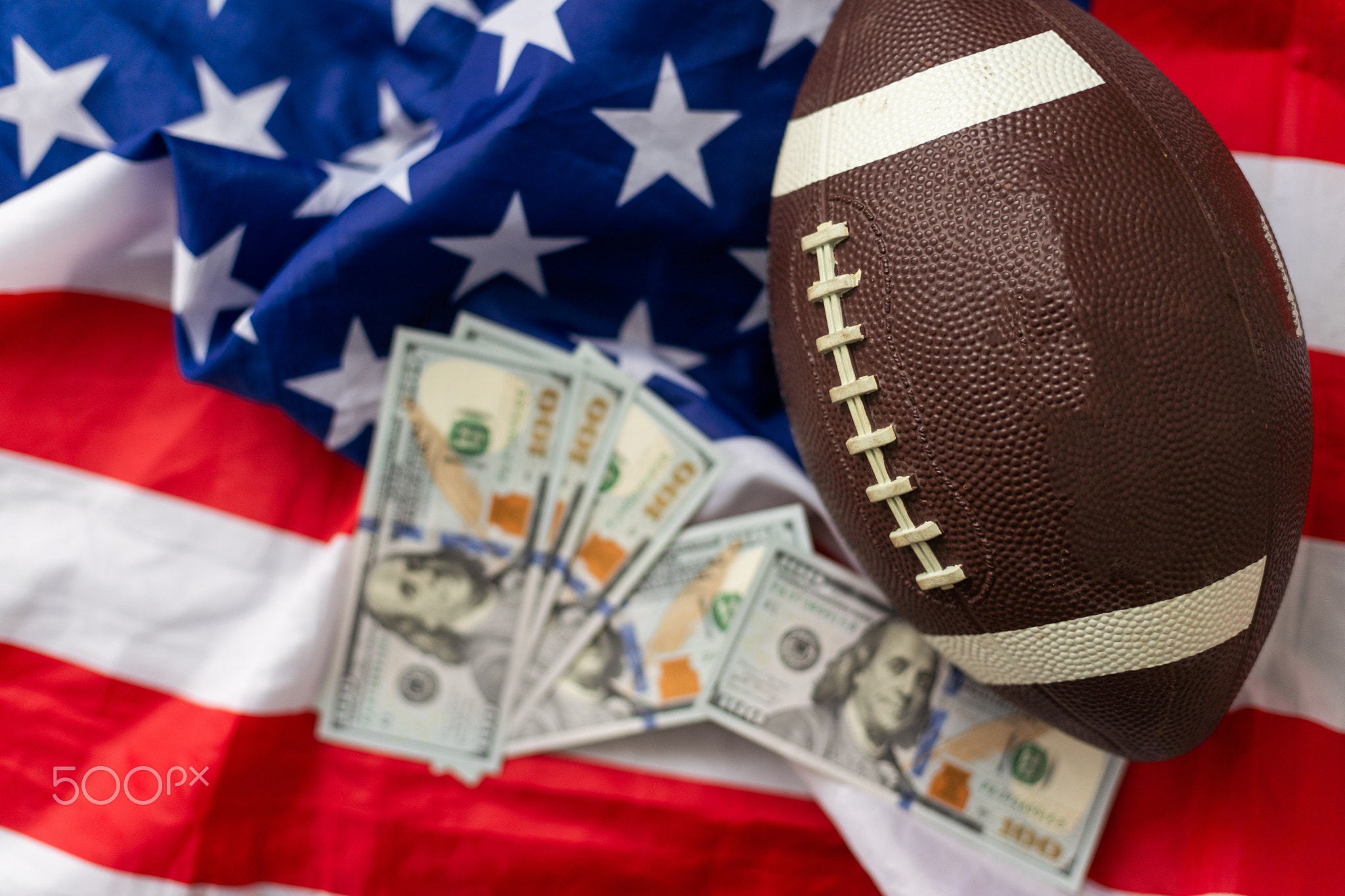 Money and rugby ball on american flag background, closeup. Concept of