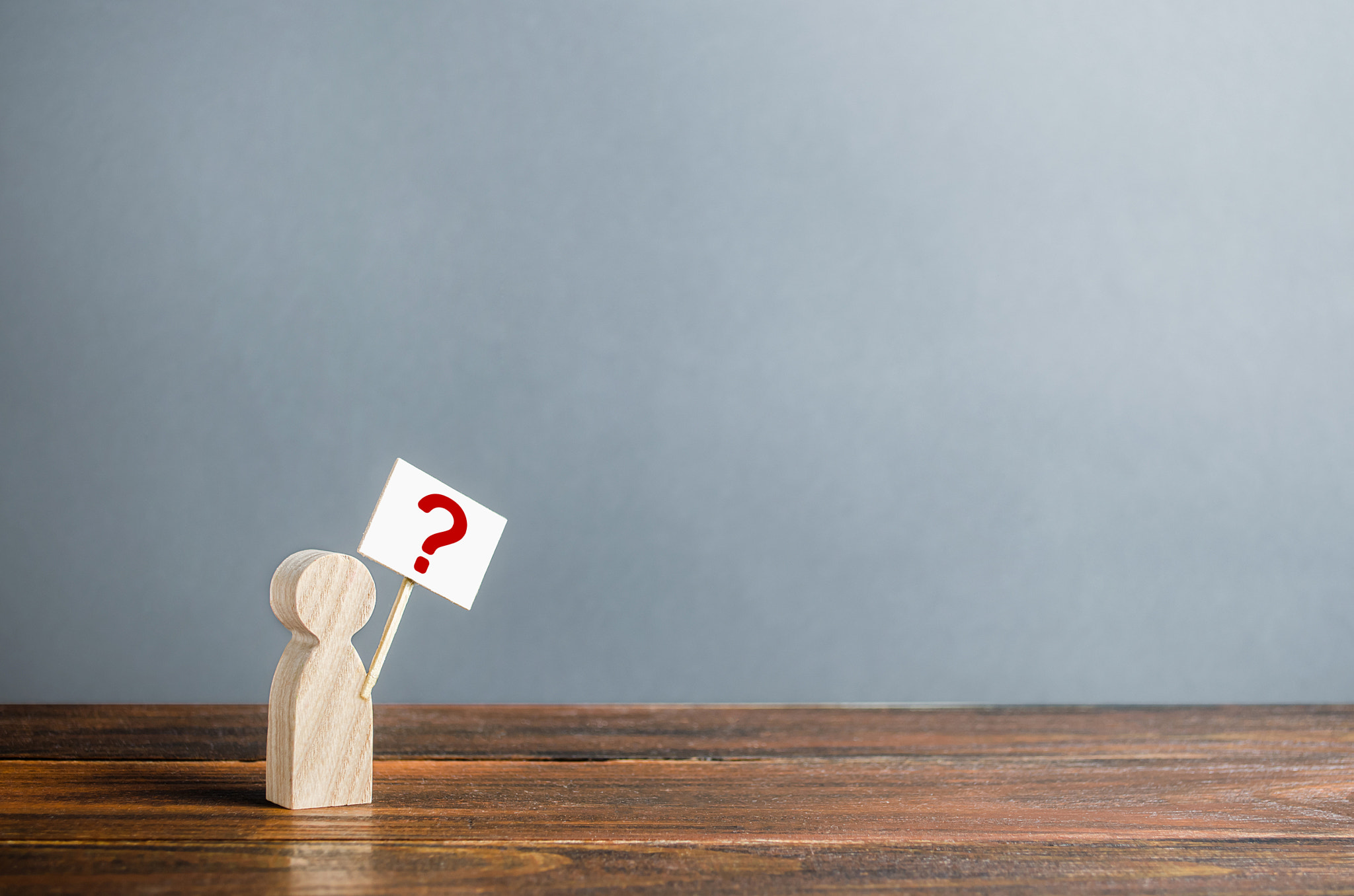 Man figurine with a poster and a question mark. Asking questions, searching for truth. Curiosity, de