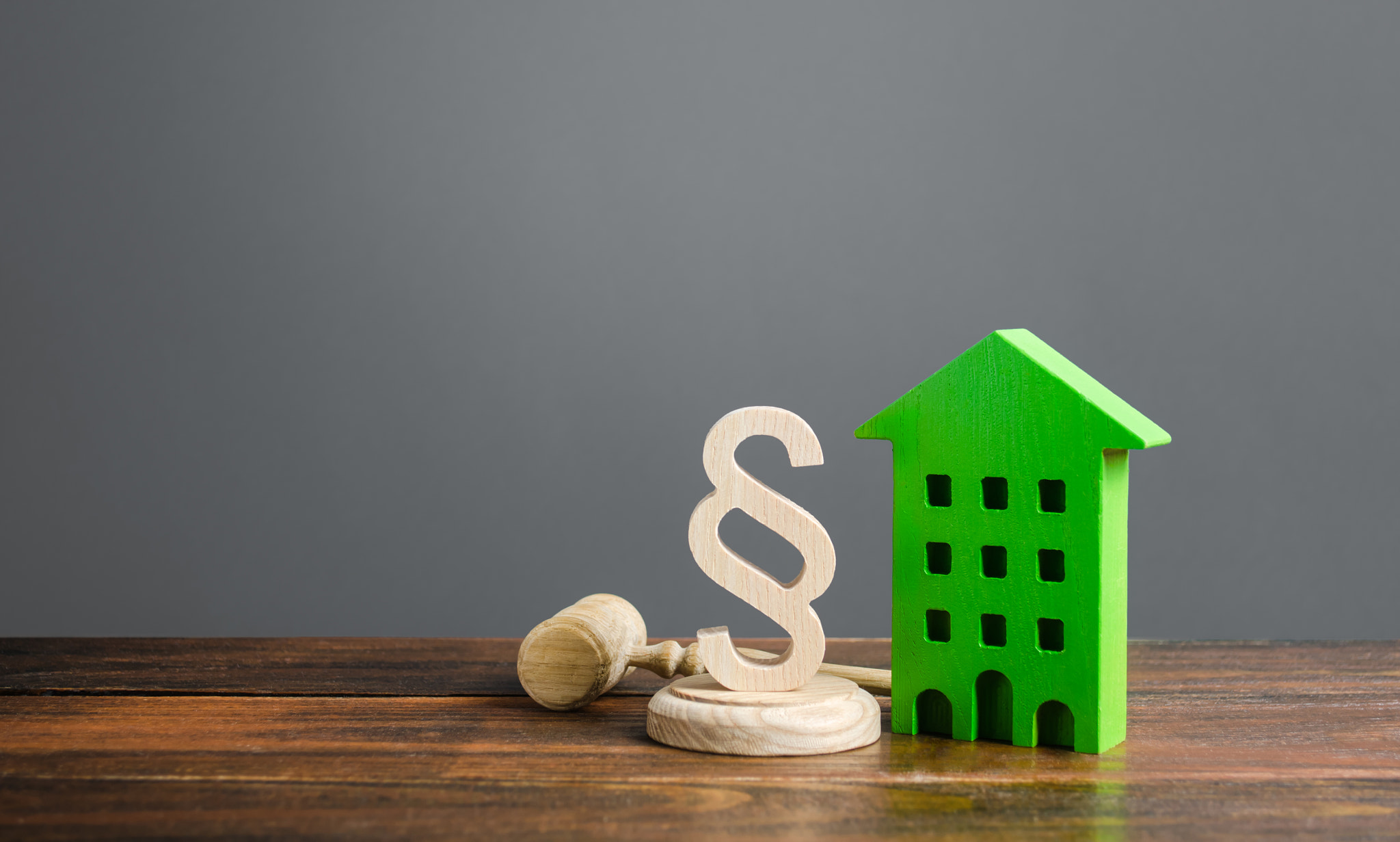 Green house and paragraph figurine with a judge hammer. Litigation in housing and real estate disput