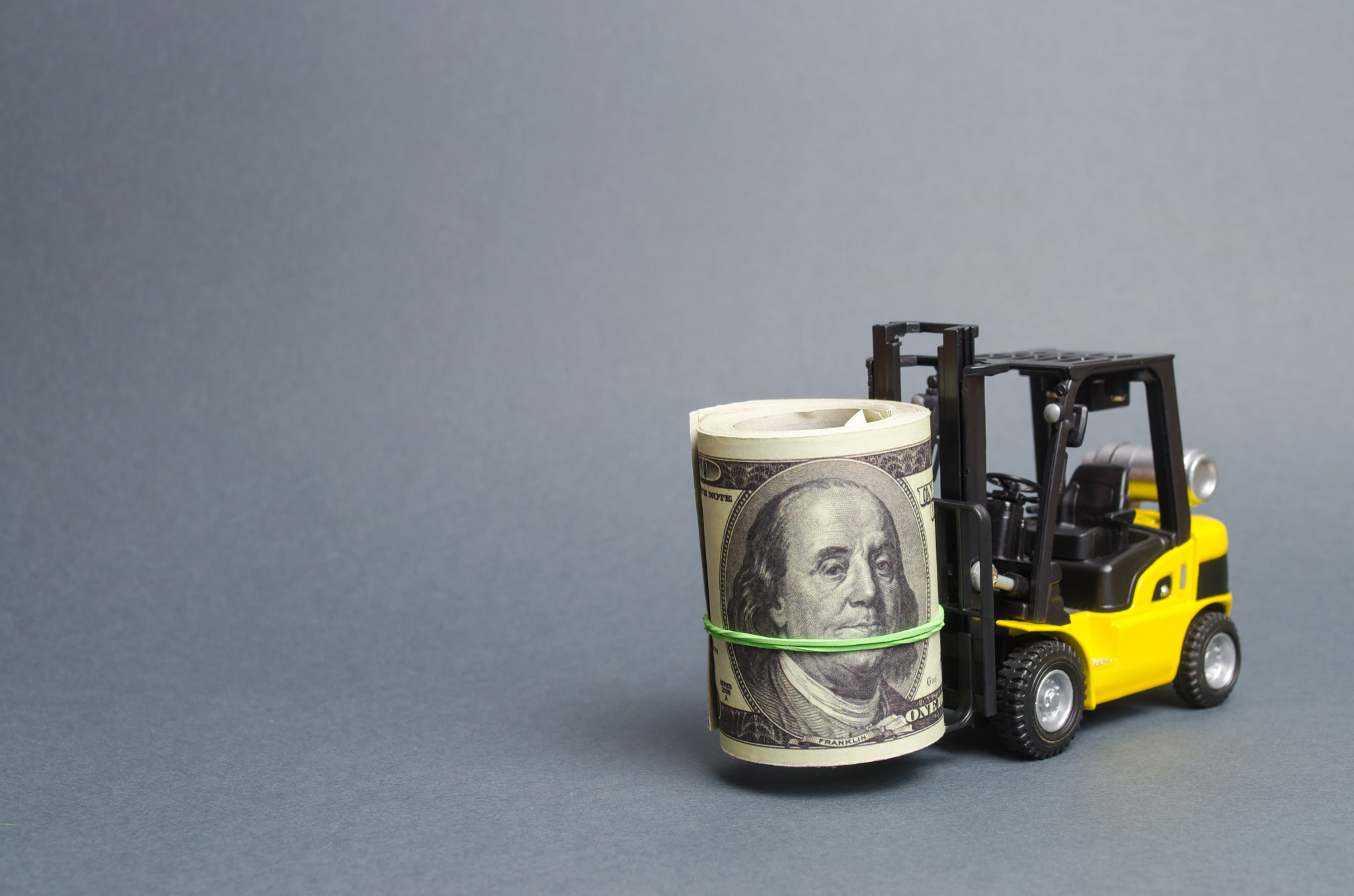 Forklift truck carries a bundle of dollars. Attracting direct investment in business and production,