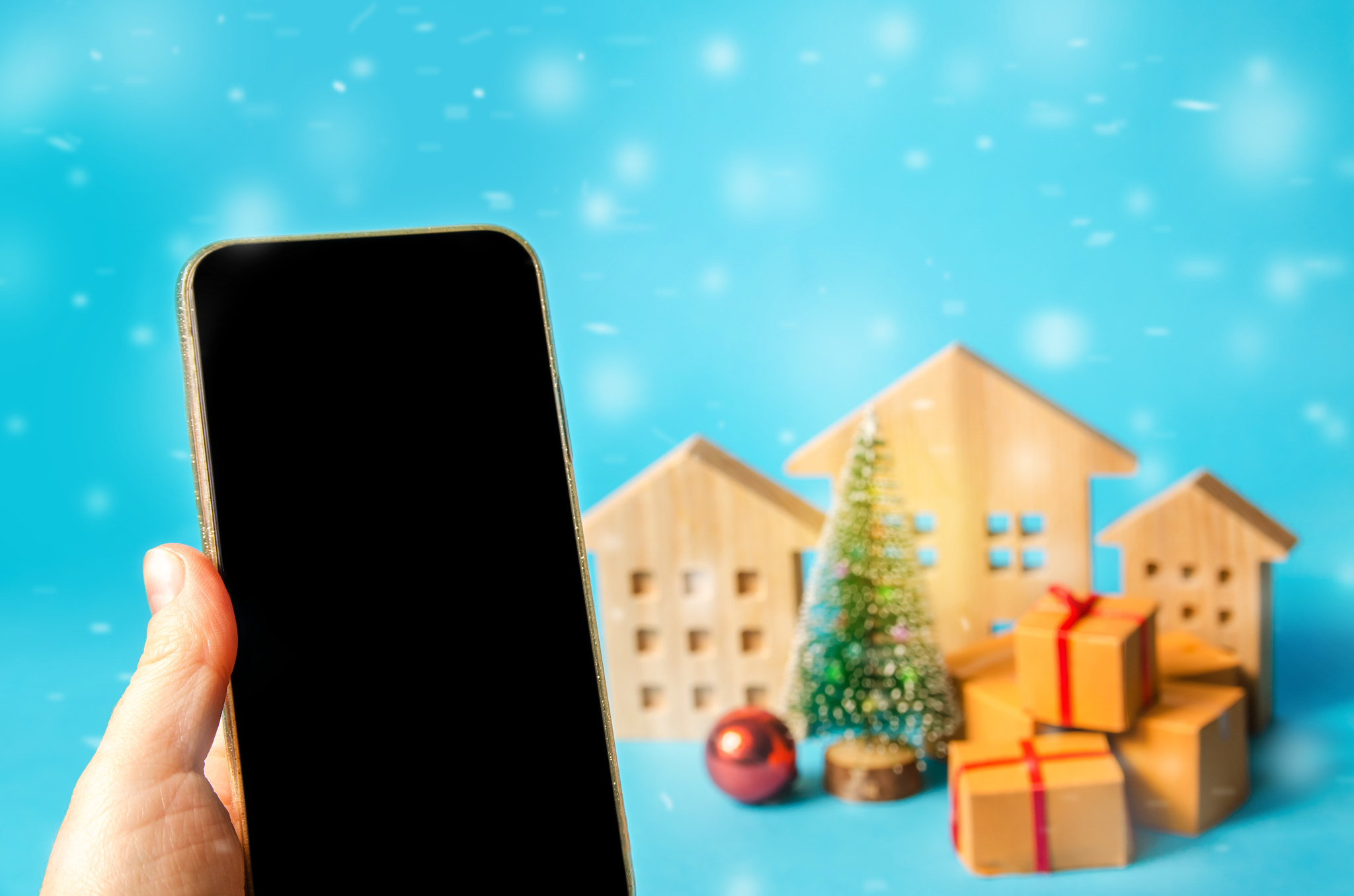 Mobile phone with blank screen and place for text, Christmas tree, houses and gifts. Online shopping