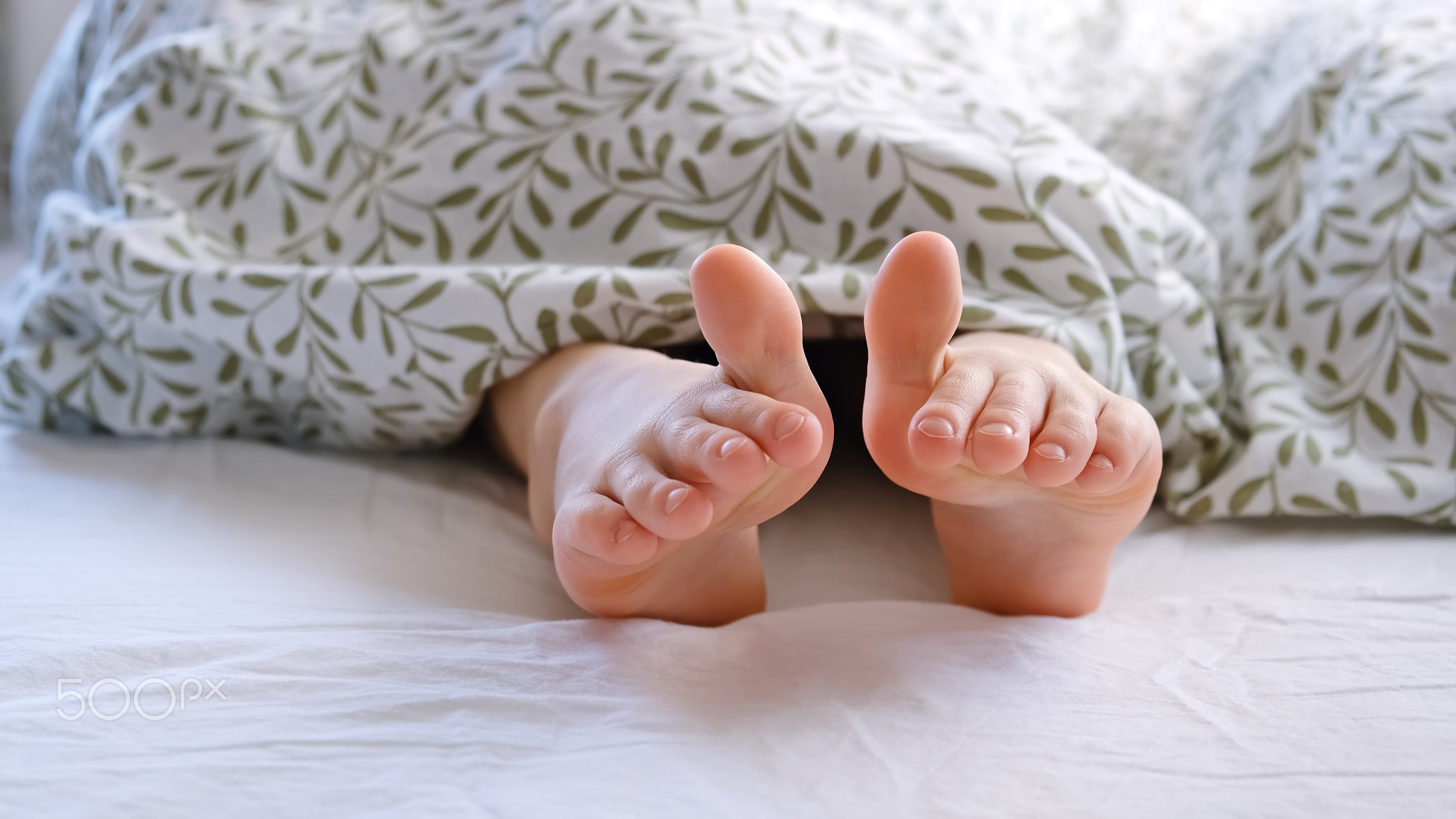 The child shows a thumbs up on his feet. Big toes. Small tender baby