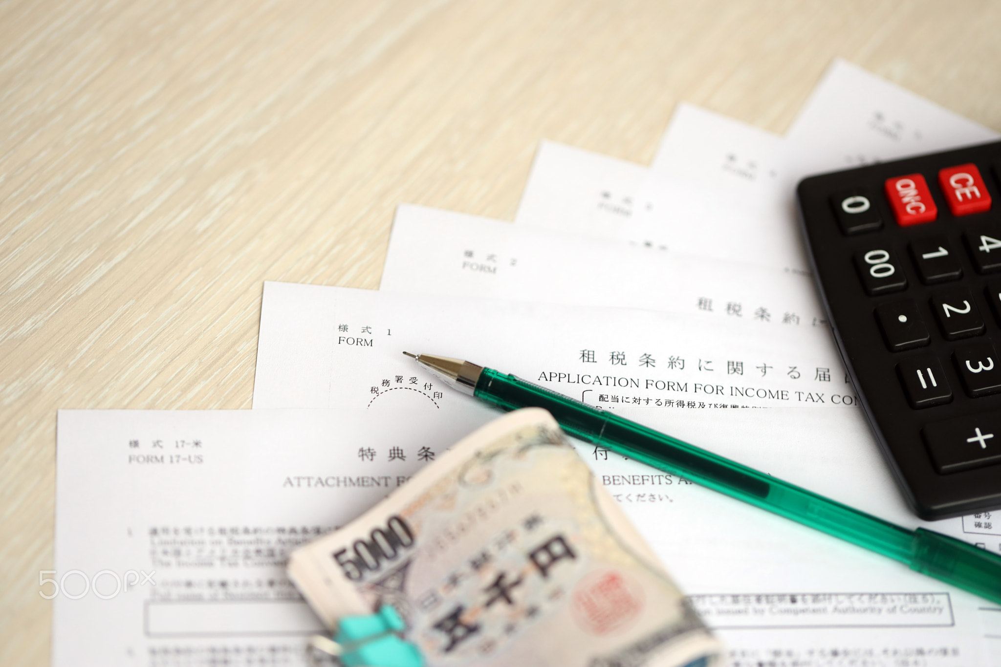 Japanese tax forms lies on table with calculator, pen and japanese yen money bills roll