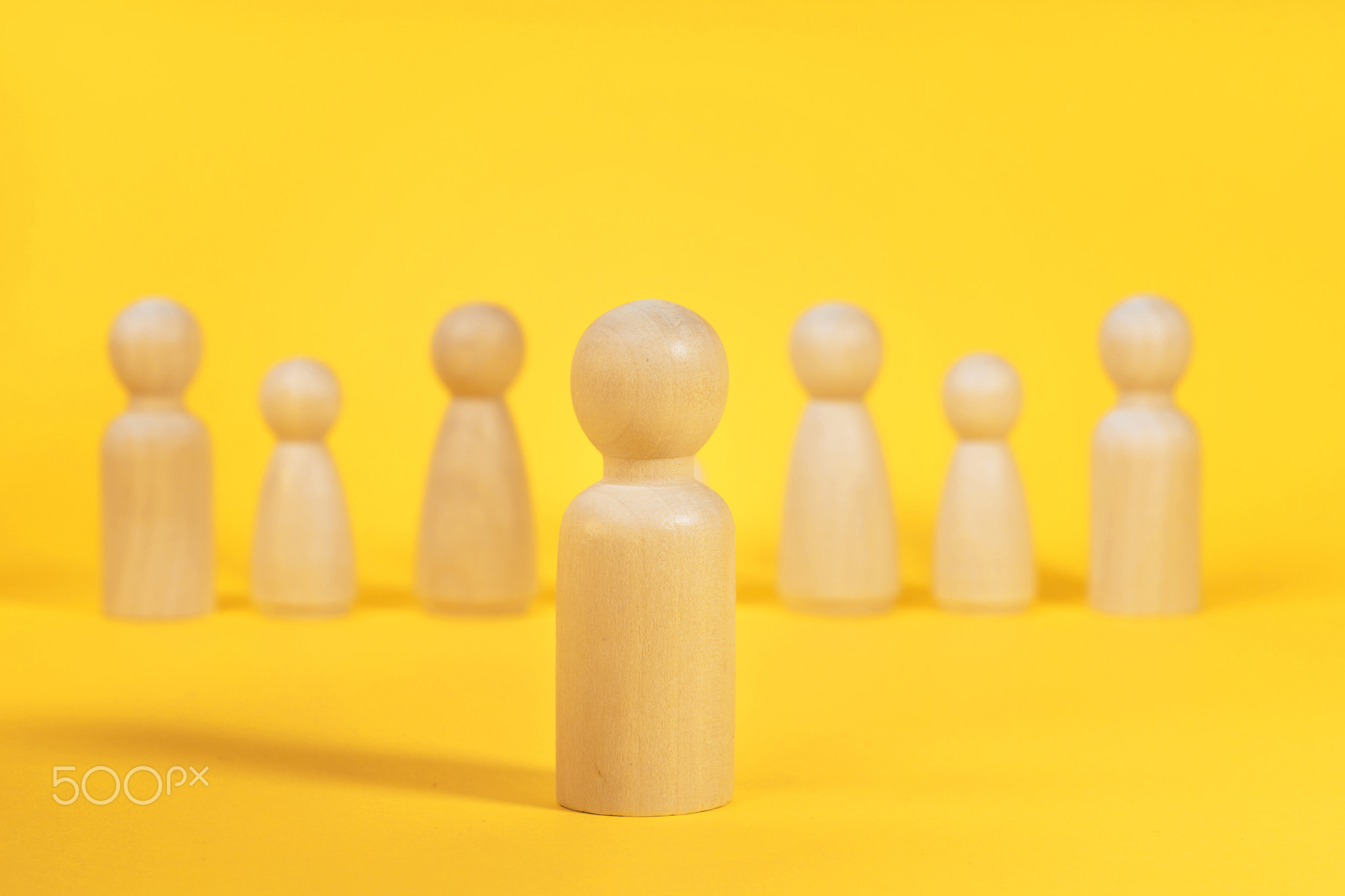 Concept of leader or boss in a team. Wooden people on yellow.