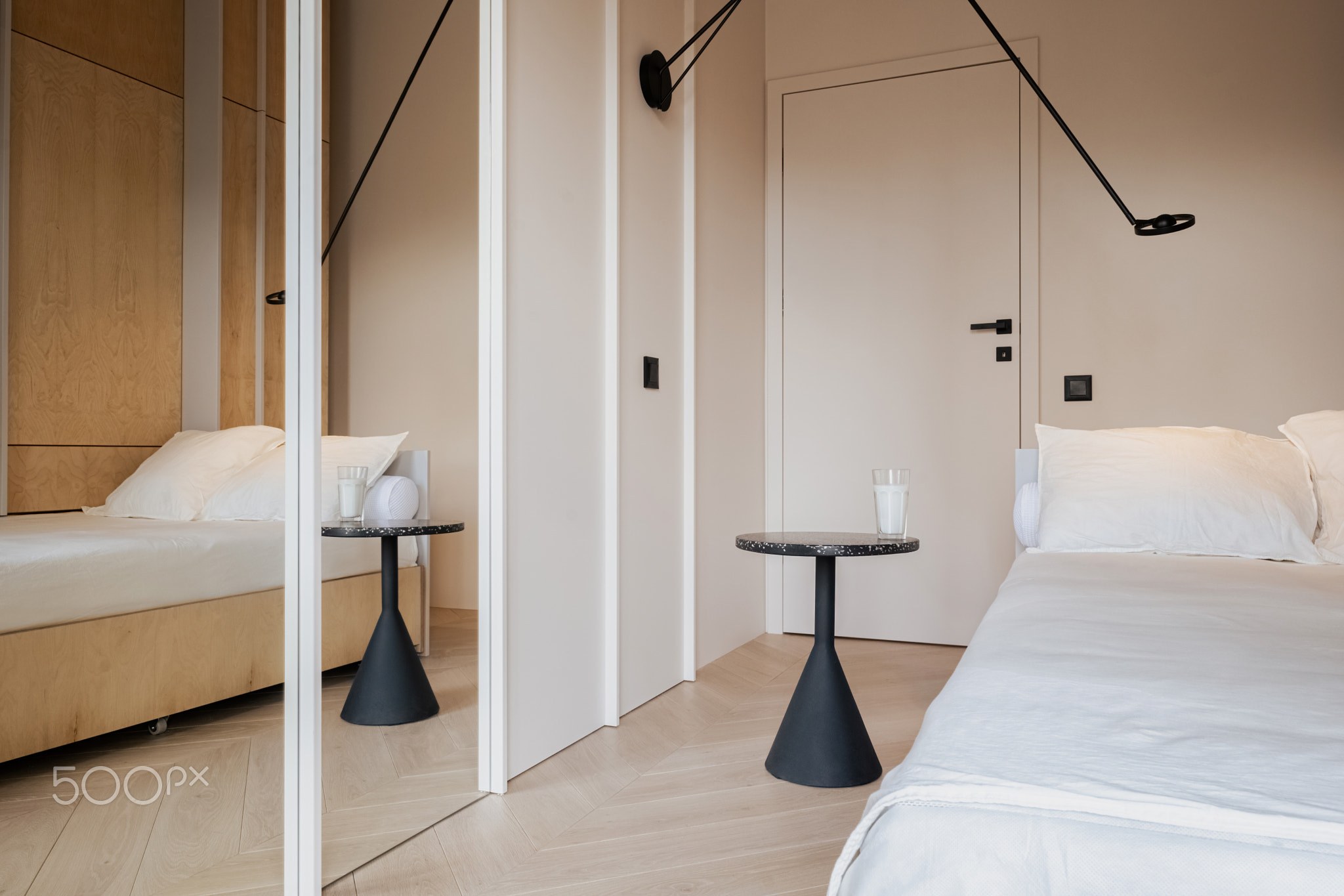 Bedroom with wooden bed, tables, mirror. Comfortable hardwood flooring