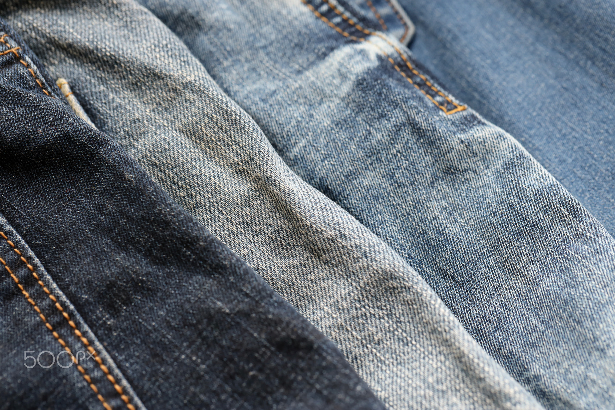 Many jeans in stack in wardrobe room. Row of pants denim jeans in closet. Concept of buy, sell