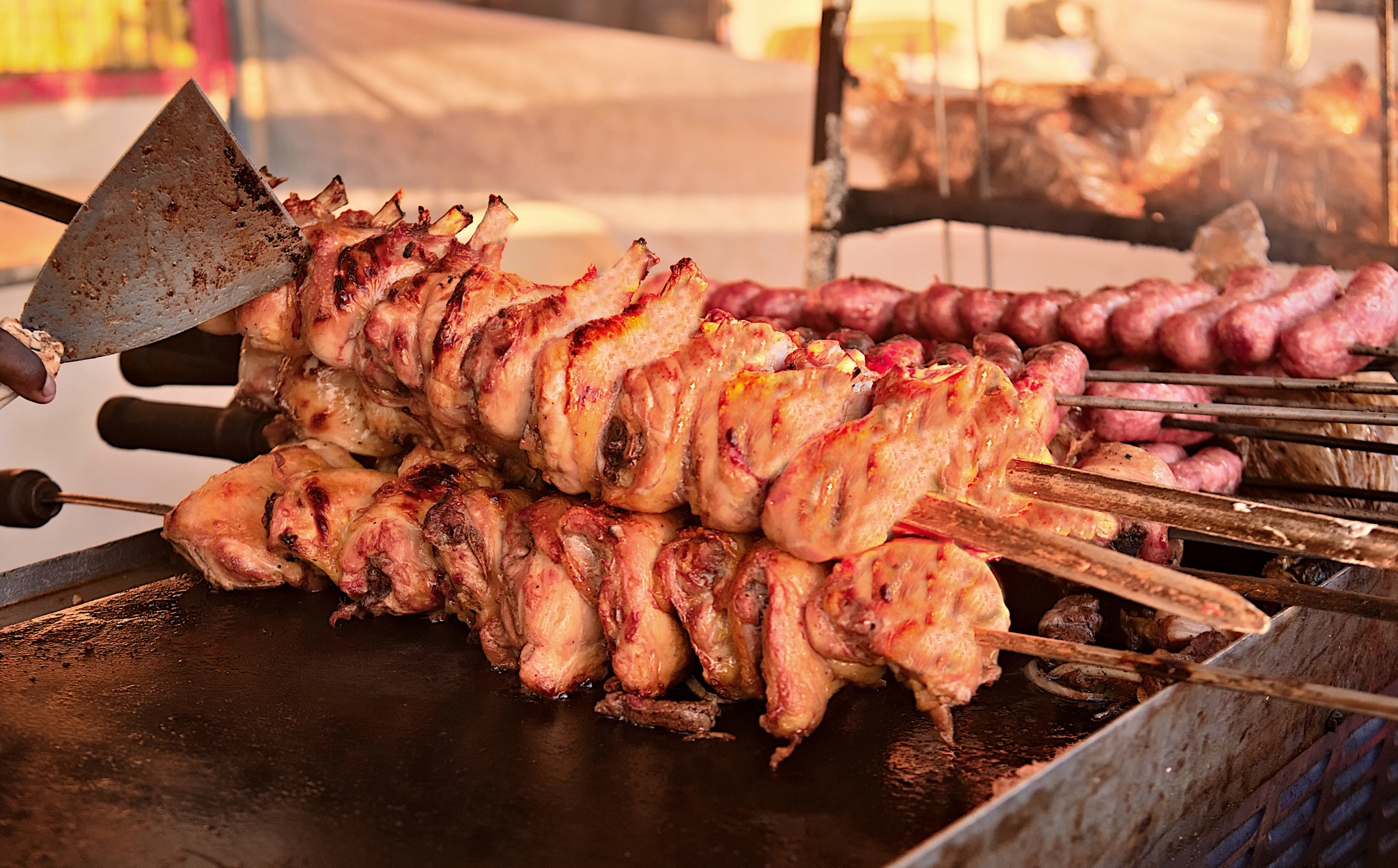 Chickens and sausages on skewers being cooked in large numbers. Street food