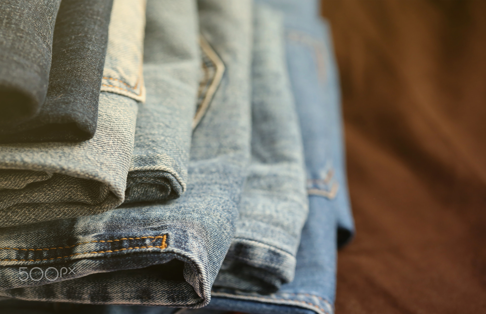 Many jeans in stack in wardrobe room. Row of pants denim jeans in closet. Concept of buy, sell