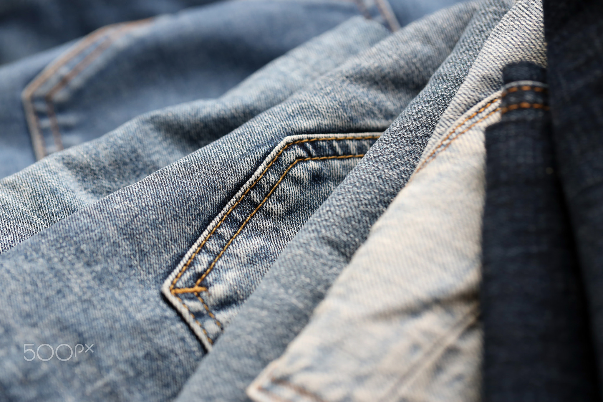Many jeans in stack in wardrobe room. Row of pants denim jeans in closet. Concept of buy, sell
