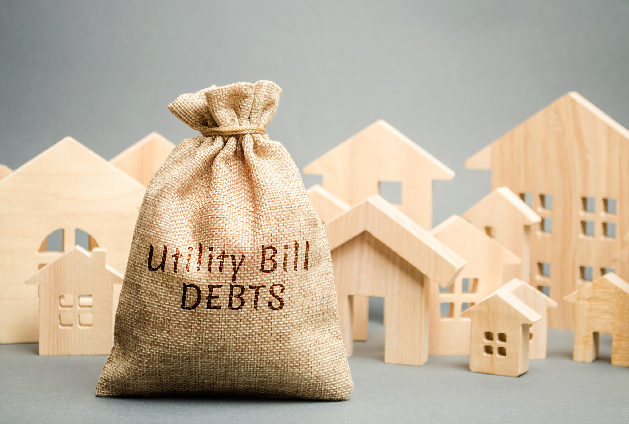 Money bag with the words Utility bill debts and wooden houses. Fines and penalties for failure to pa