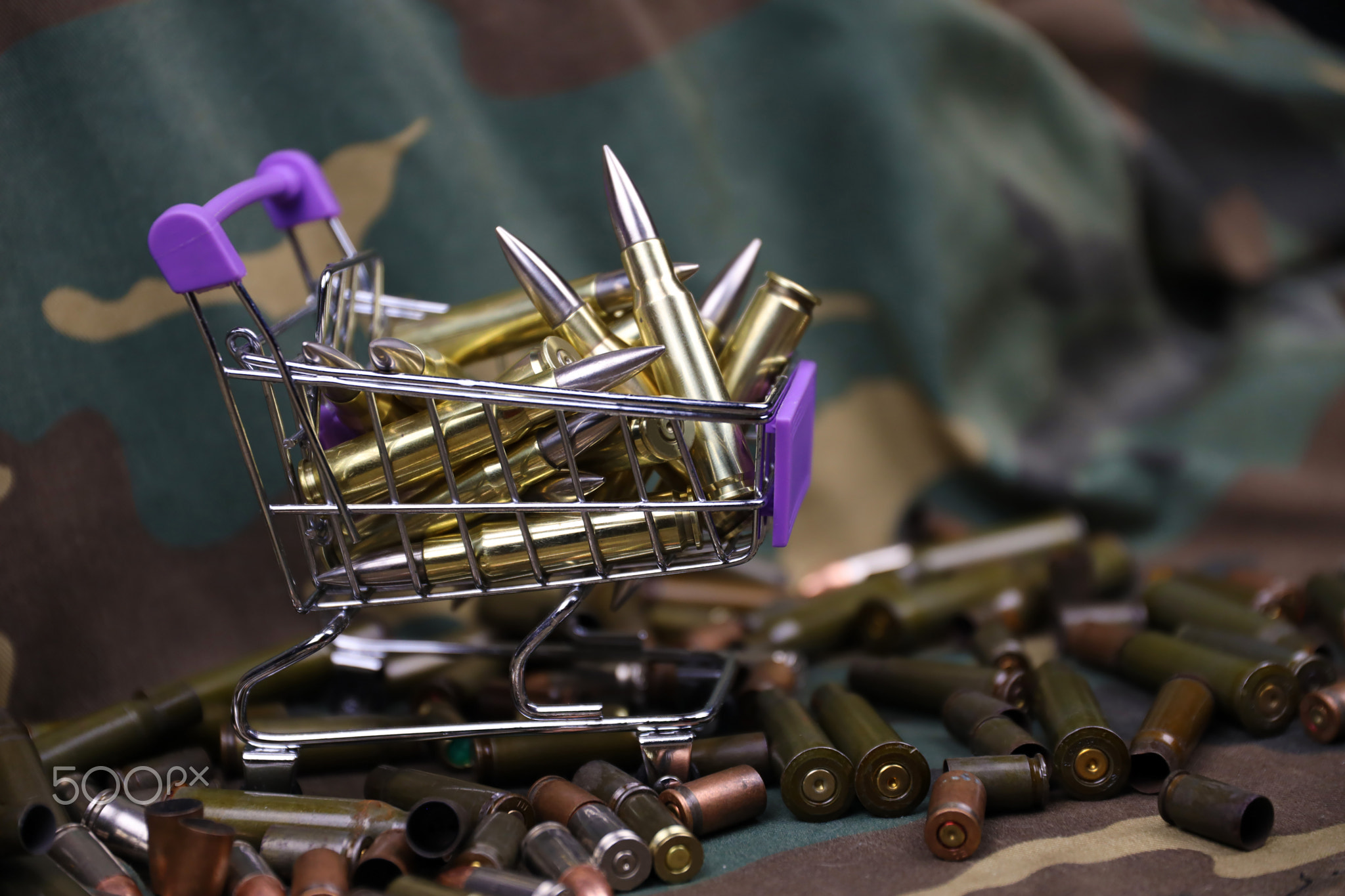 Rifle cartridges in small shopping cart. Big caliber ammo cartridges with a small shopping basket