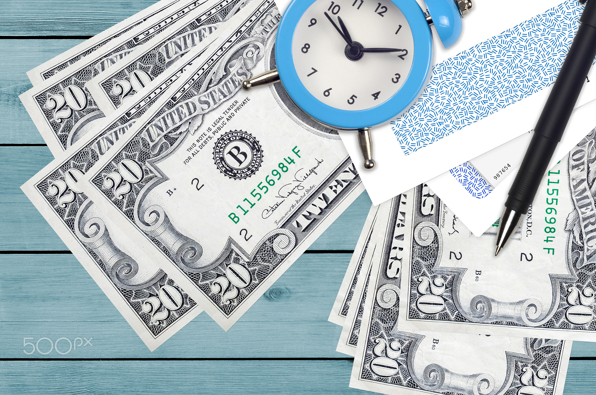 20 US dollars bills and alarm clock with pen and envelopes. Tax season concept, payment deadline for