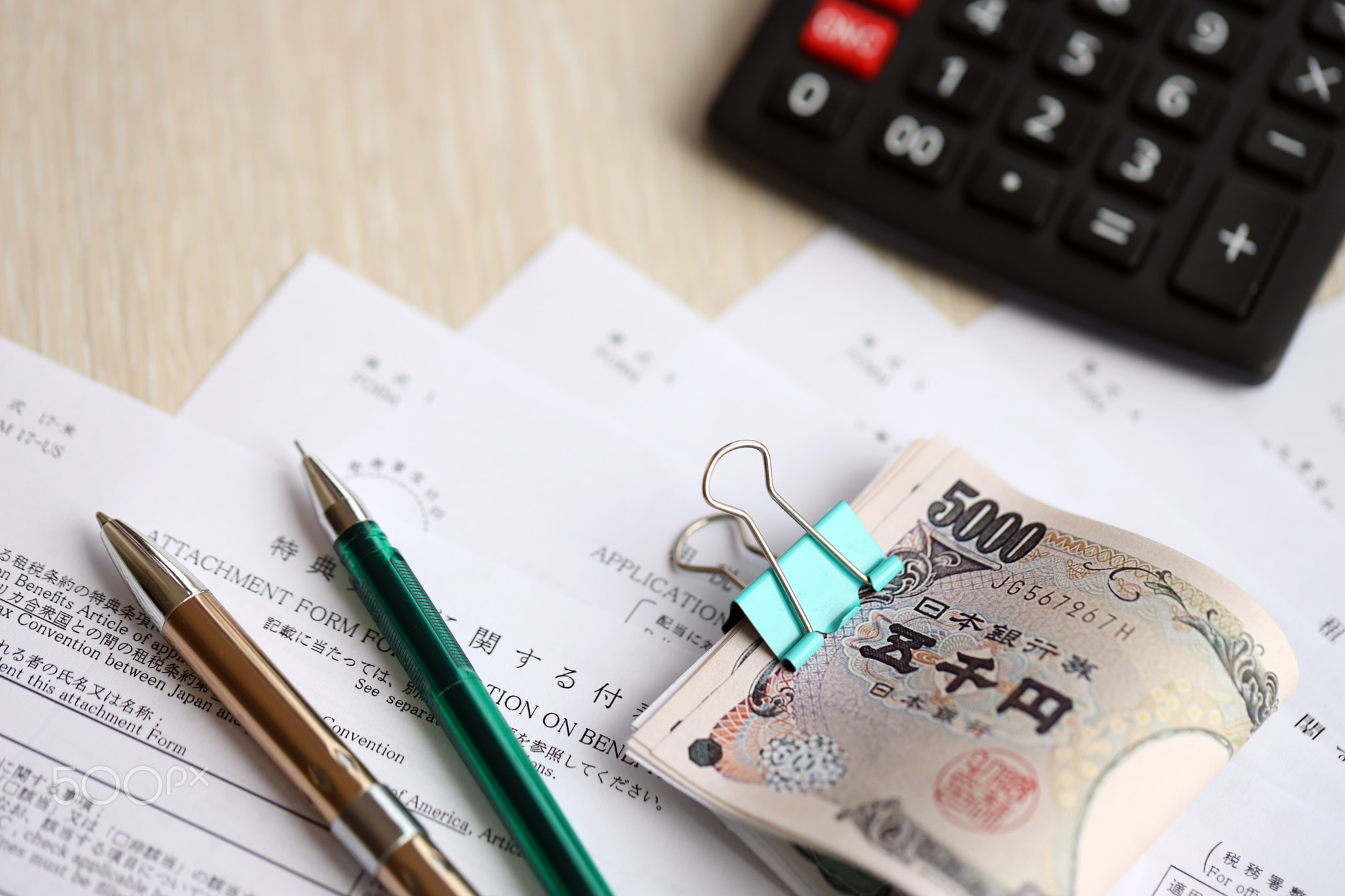Japanese tax forms lies on table with calculator, pen and japanese yen money bills roll